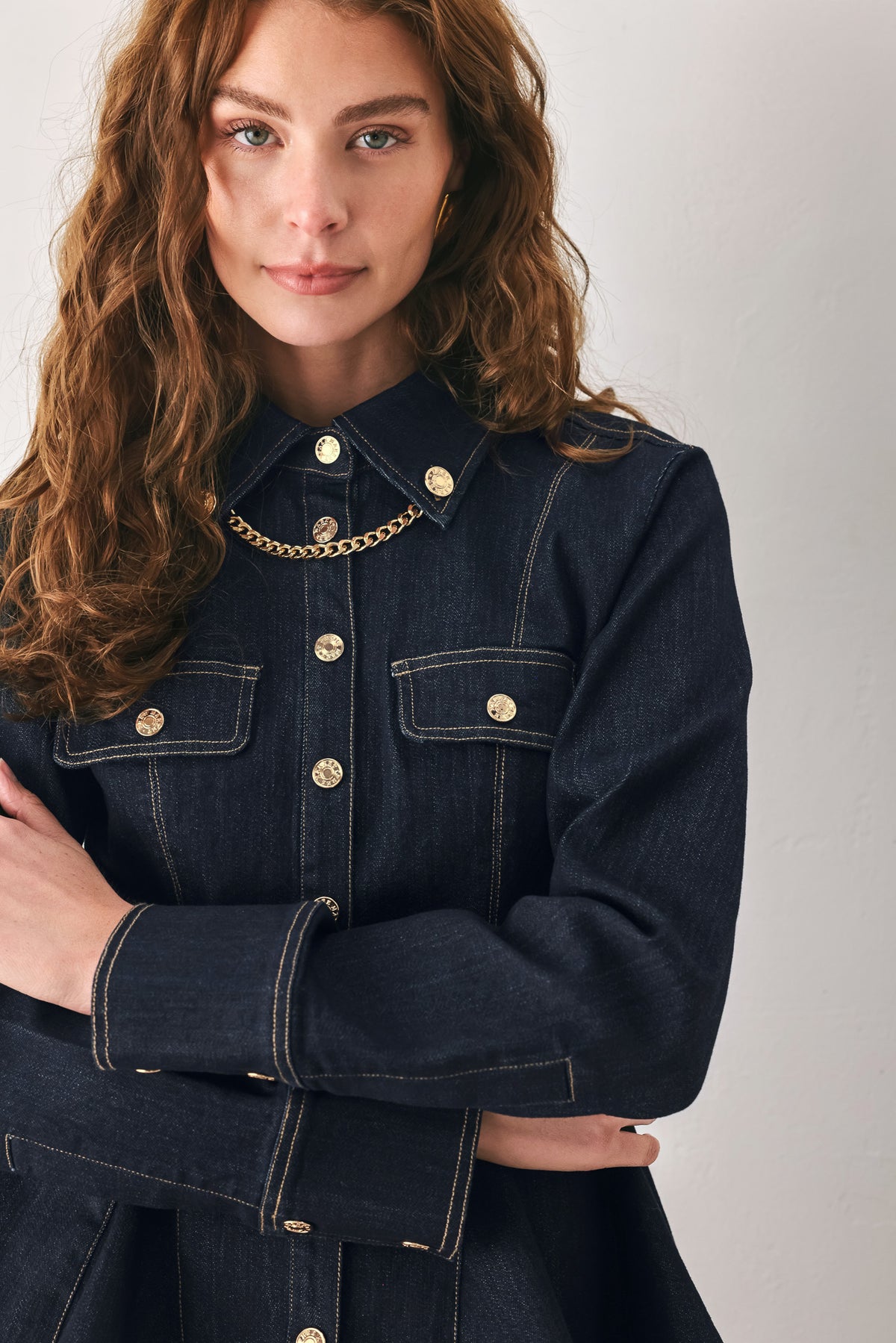 Woman wearing a navy blue denim long sleep button up top with a peplum waist, a collar and chain connected to the corners of the collar | FREEMARKET