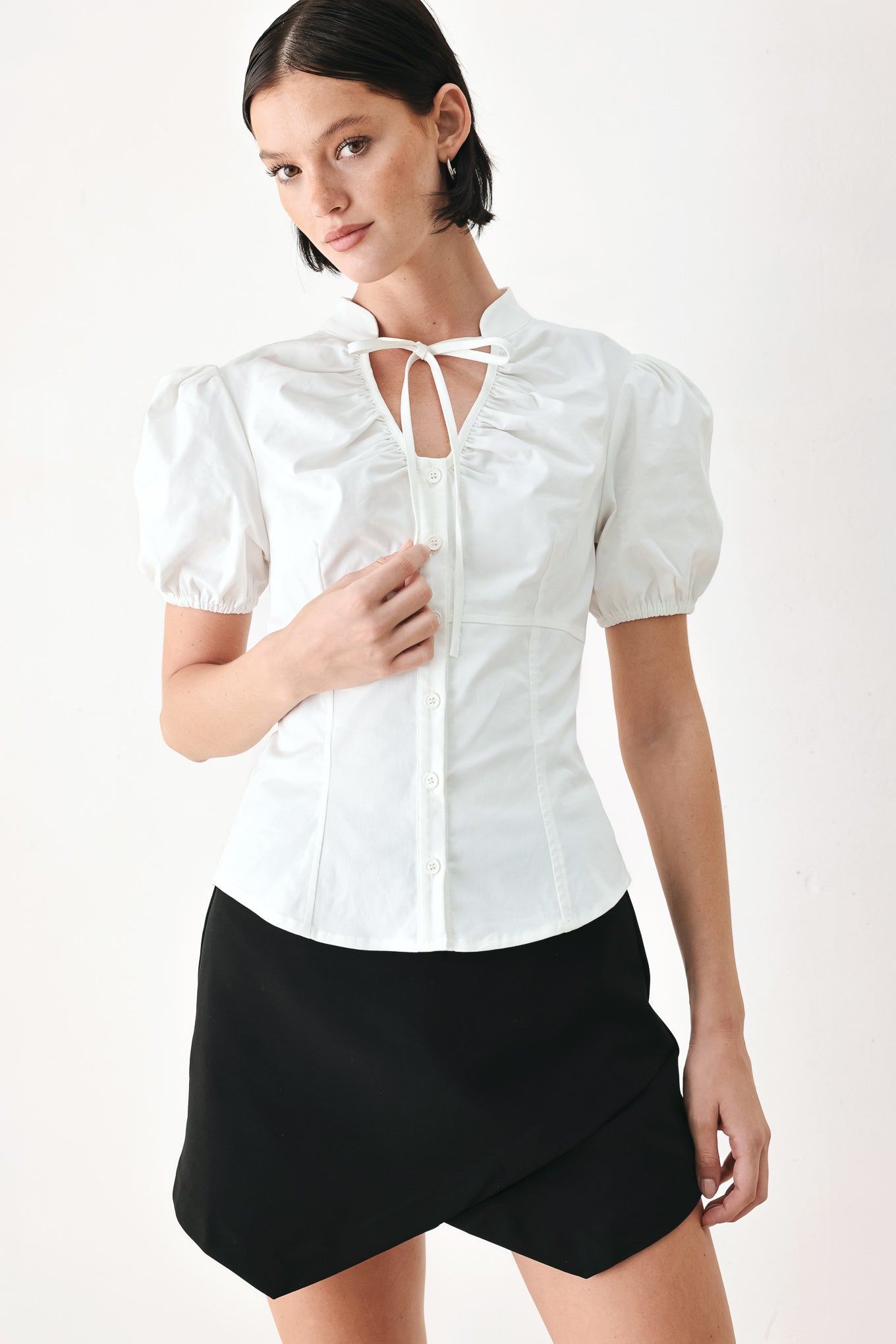 A woman wearing a white short-sleeve blouse with puff sleeves, a ruffled collar, and a keyhole cutout at the neckline | FREEMARKET