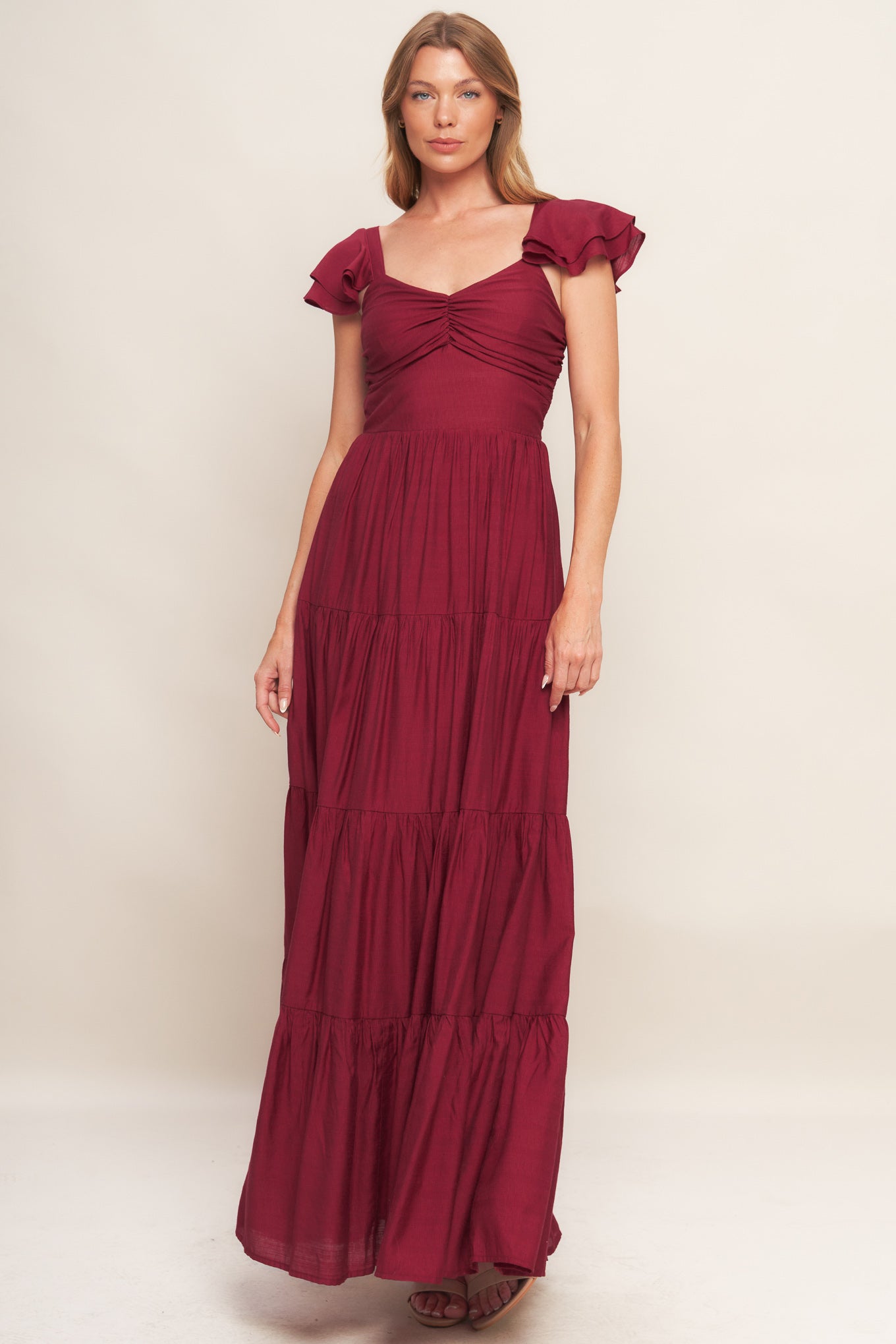 A solid woven maxi dress featuring cami top with layered sleeve, cinched front bodice, tiered skirt and smocked back bodice.