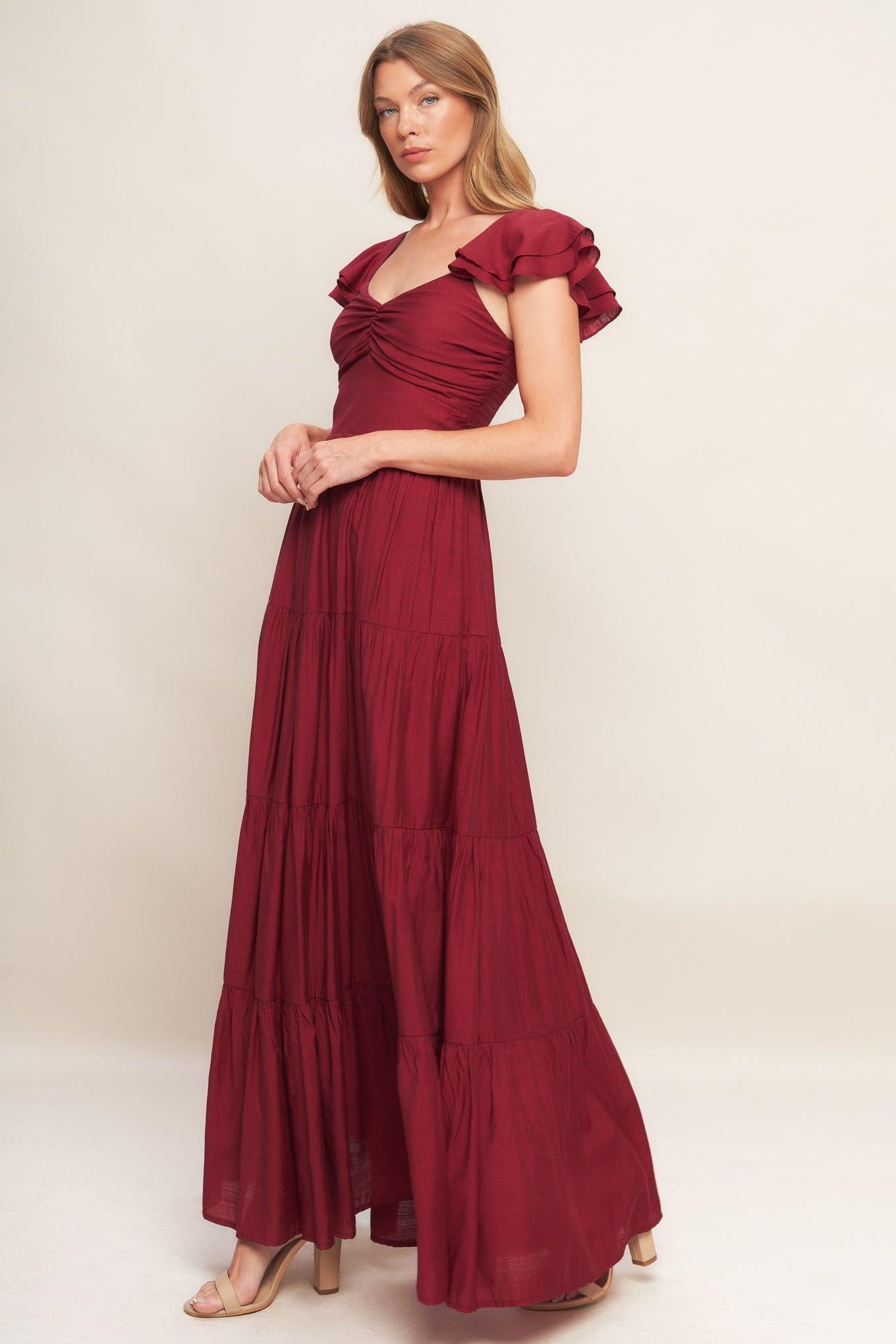 A solid woven maxi dress featuring cami top with layered sleeve, cinched front bodice, tiered skirt and smocked back bodice. FLYING TOMATO