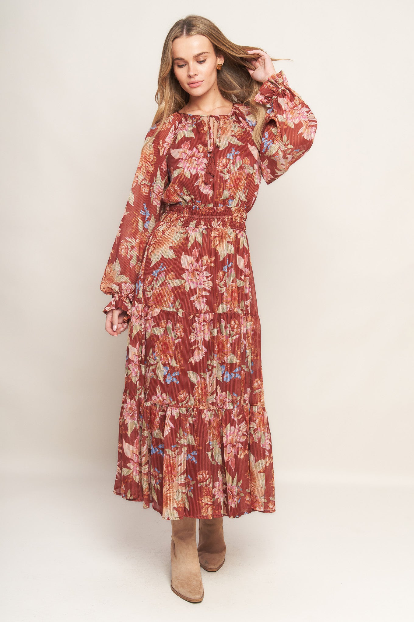 A printed woven midi dress featuring round neckline with front tie, long sleeve, elasticized waist and tiered skirt