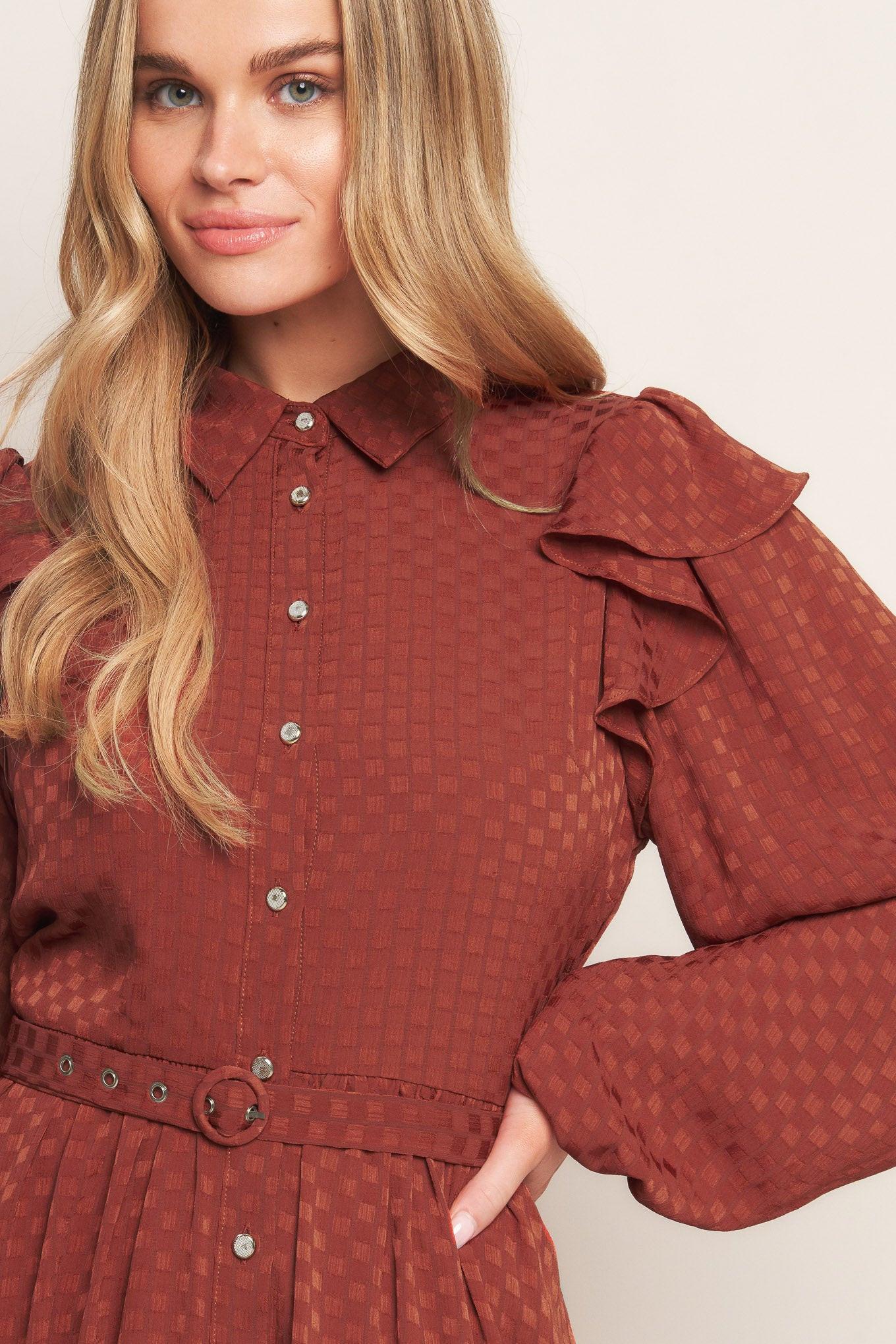 A textured woven mini dress featuring shirt collar, button down, long sleeve with ruffled shoulder, self belt and full skirt