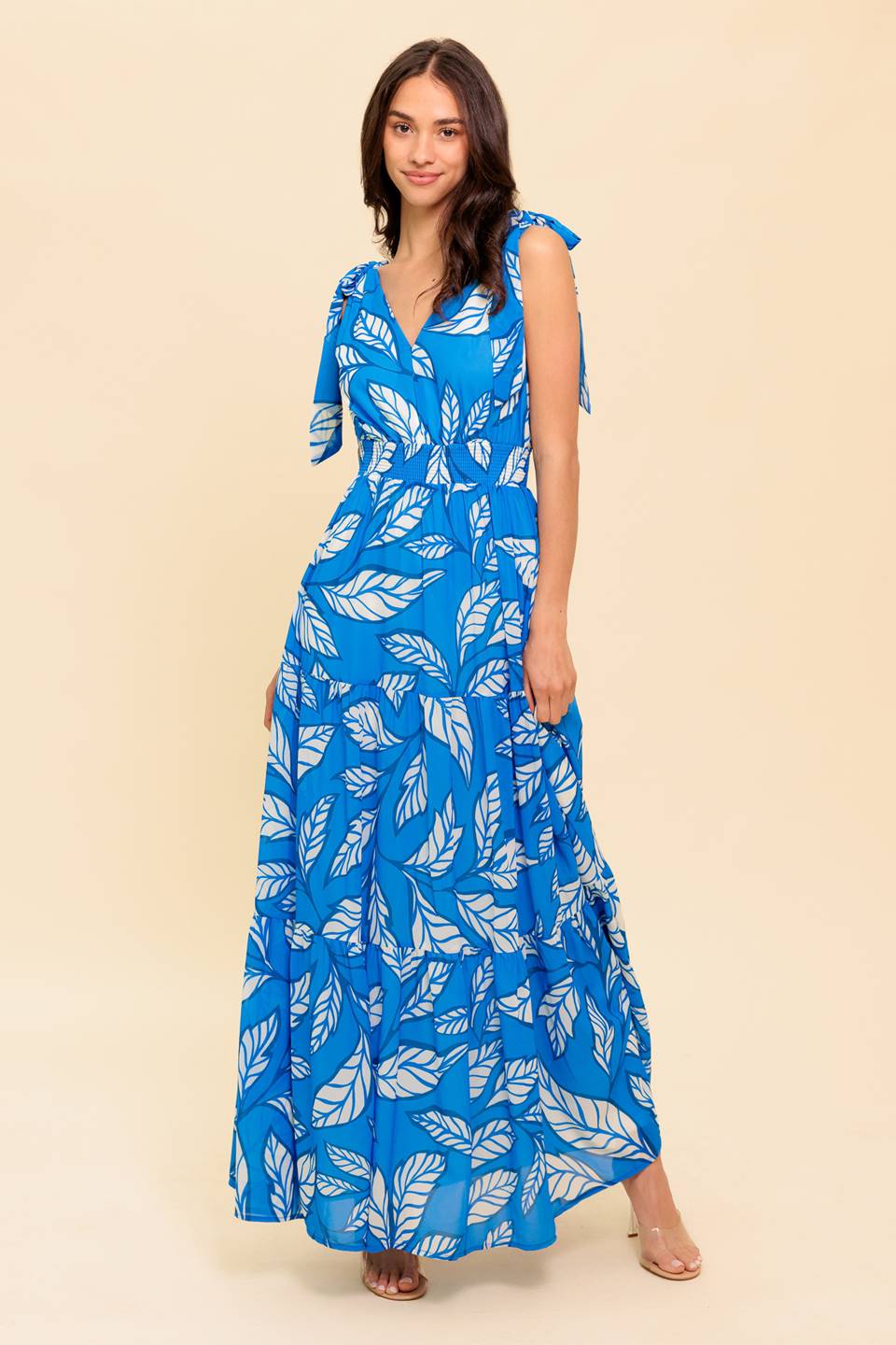 A printed woven maxi dress featuring V neckline, shoulder bow tie, smocked waistband and tiered skirt
