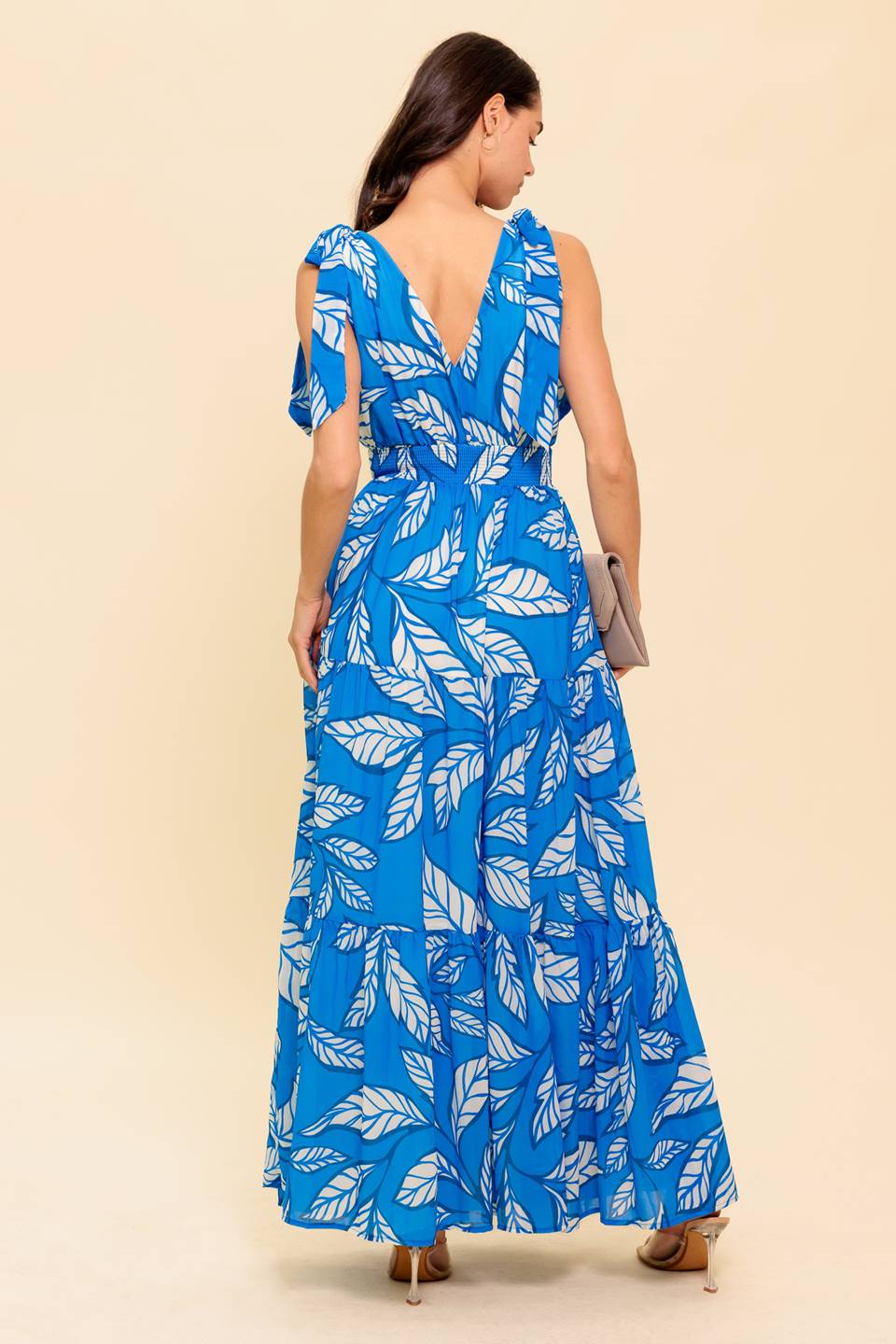 A printed woven maxi dress featuring V neckline, shoulder bow tie, smocked waistband and tiered skirt