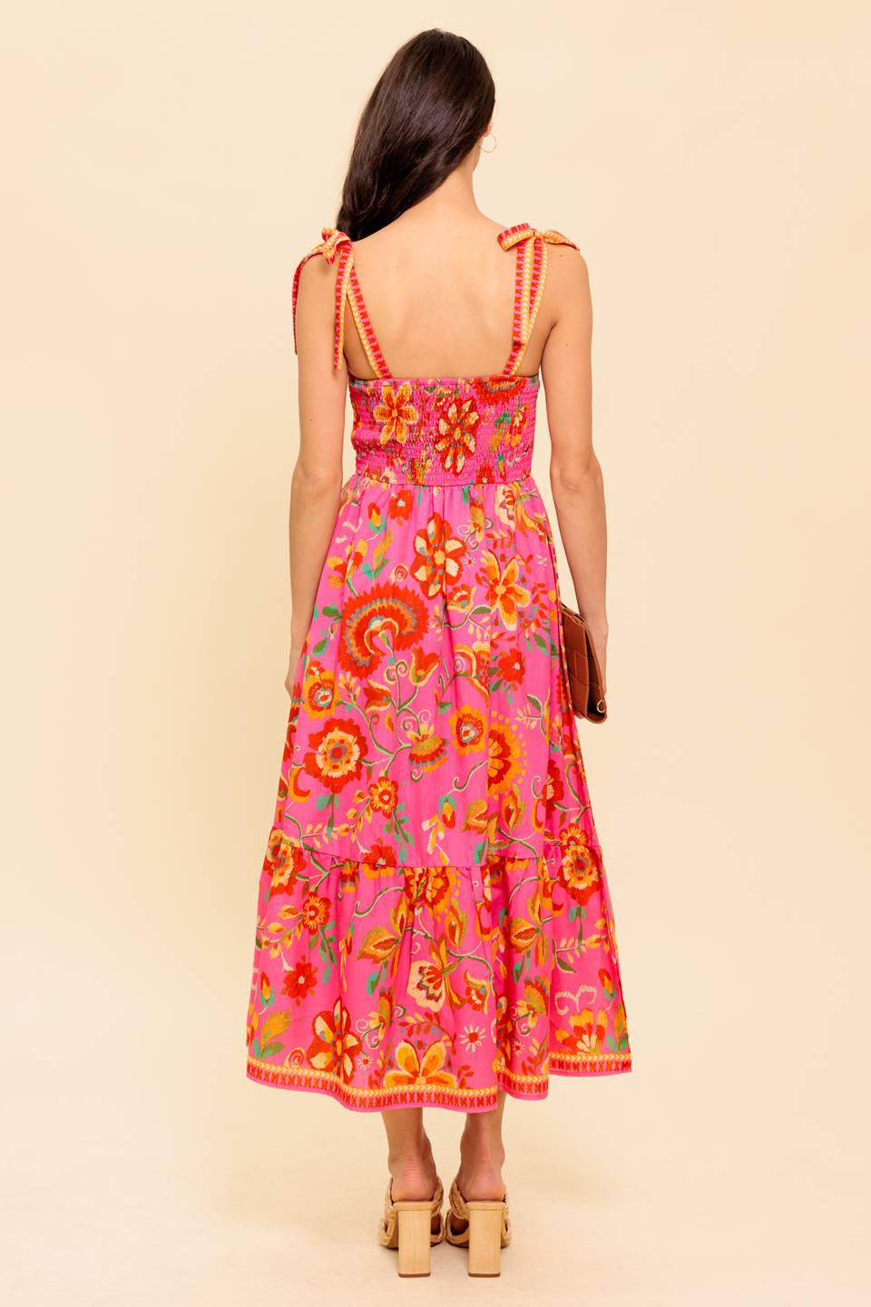 A printed woven midi dress featuring bustier top with shoulder tie, full skirt with ruffled hemline and smocked back bodice
