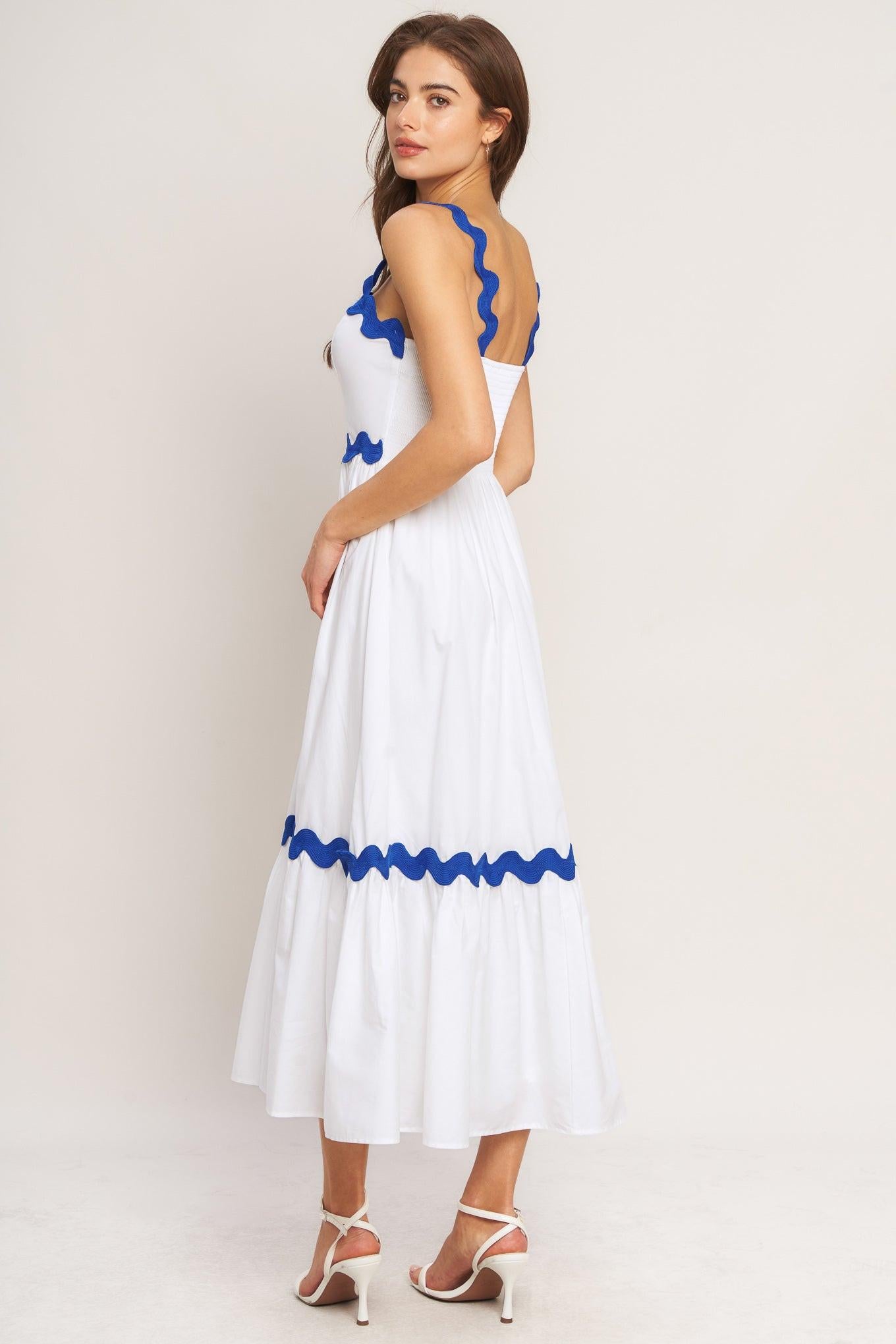 Woman wearing a white dress with blue accents on a plain background