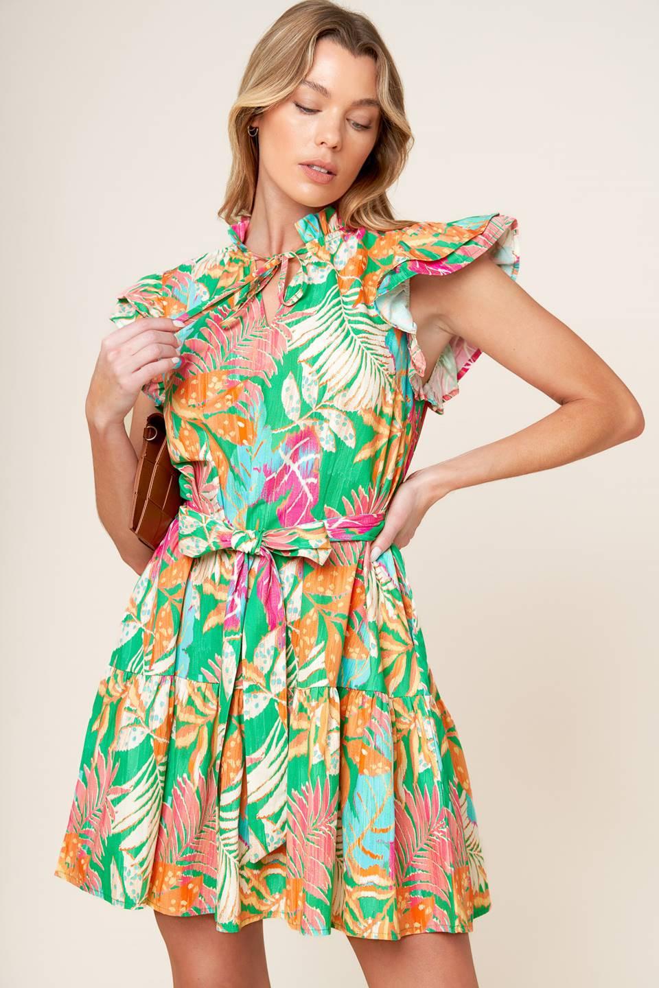 A printed woven mini dress featuring high neckline ruffled edge with front tie, double ruffled sleeve, self sash tie and ruffled hemline.