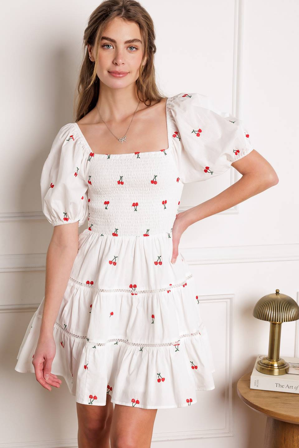 A cute embroidered mini dress with a square neckline, short puff sleeves, smocked bodice and a tiered skirt with lace detailing.