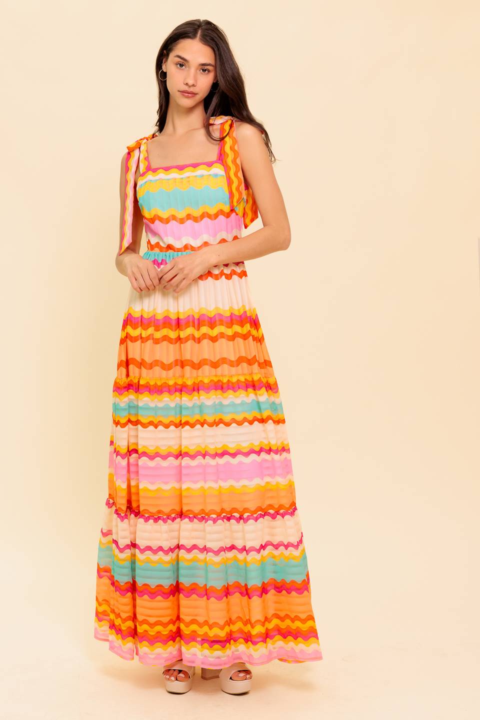 A printed woven maxi dress featuring straight neckline, shoulder ties, tiered skirt and back zipper closure