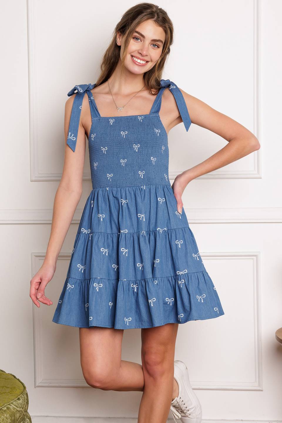 A chic woven mini dress with a solid embroidered design and charming shoulder ties, complete with a smocked bodice and tiered skirt.