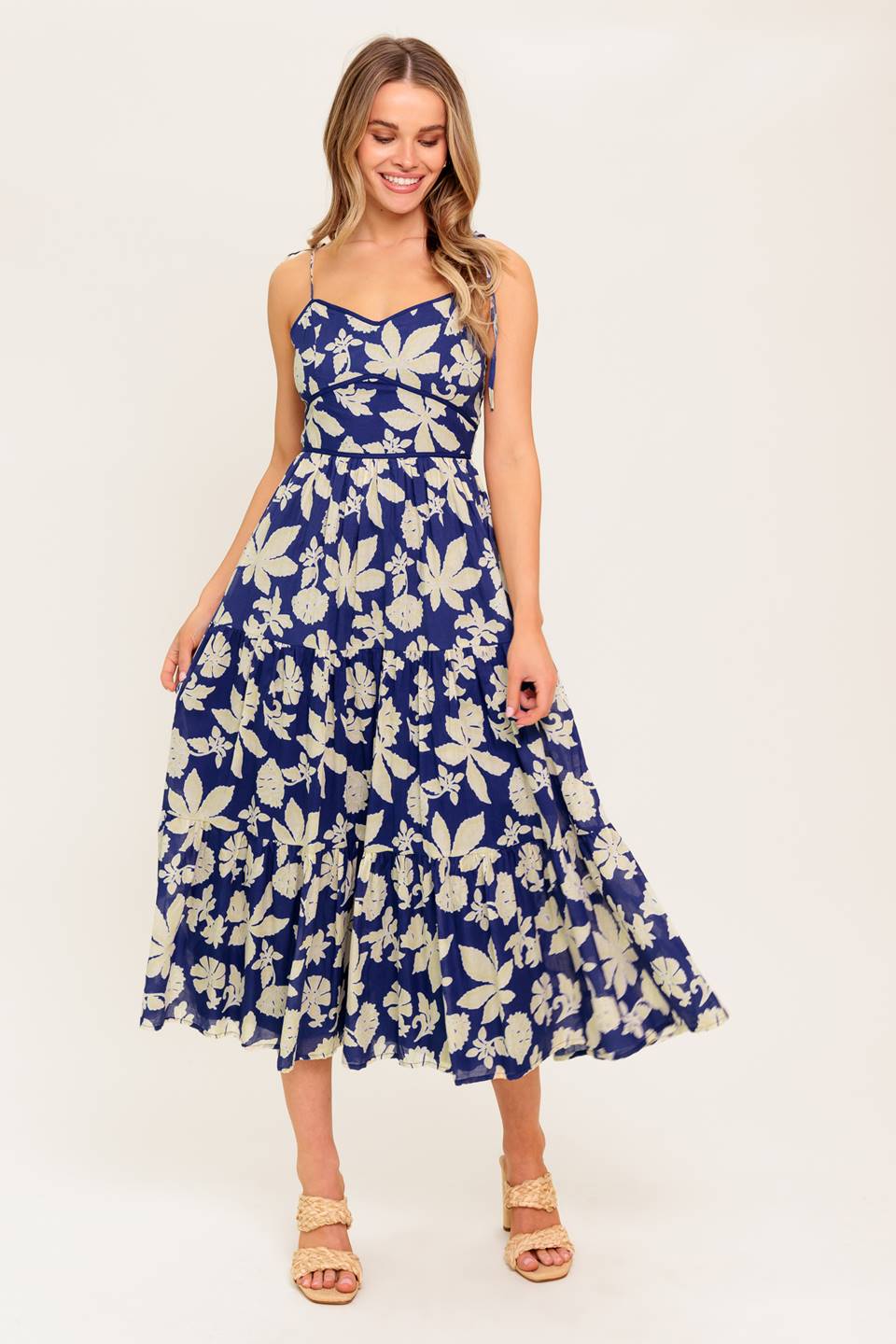 A printed woven midi dress featuring sweetheart neckline, shoulder tie, waist yoke, tiered skirt and back zipper closure.
