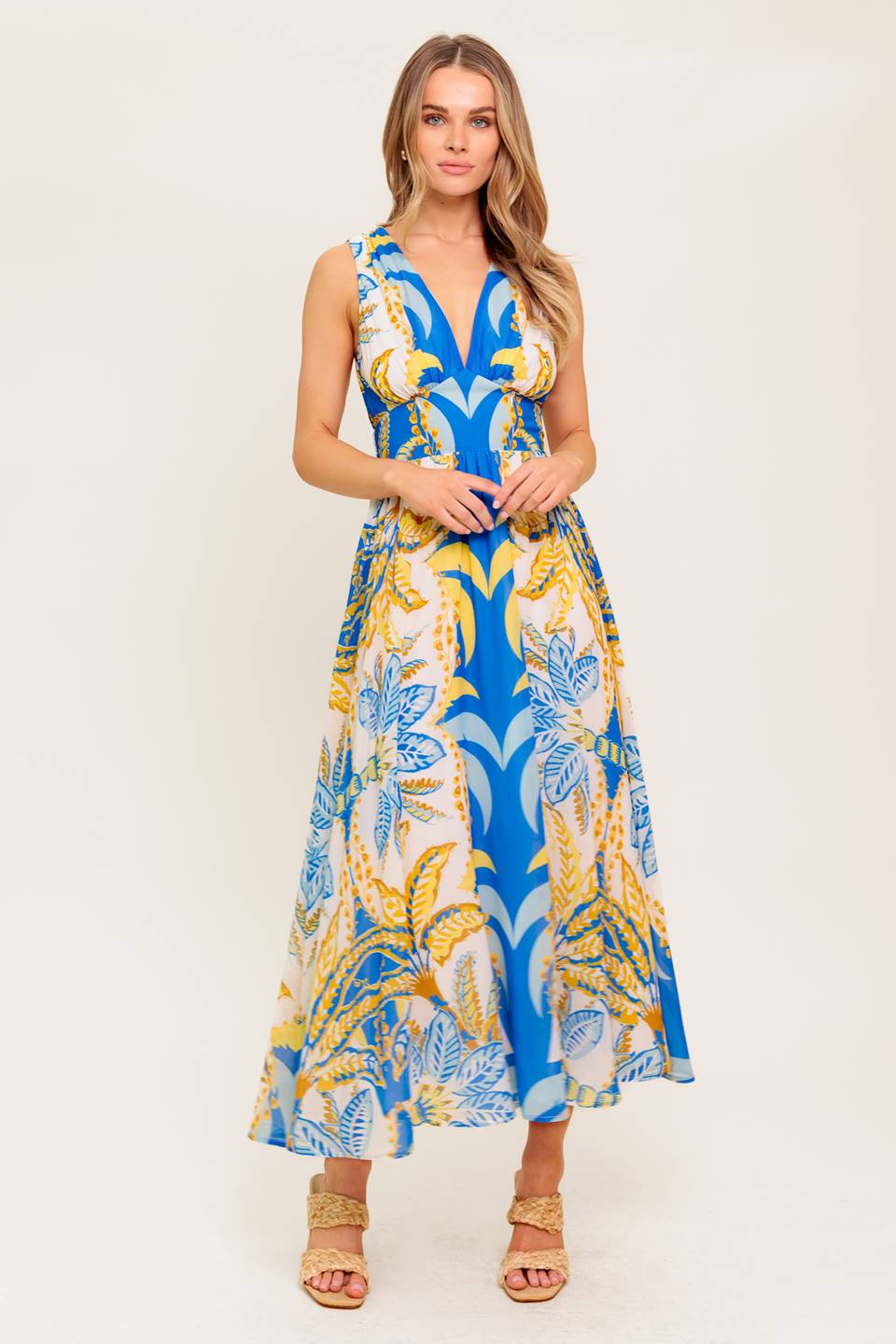 A printed woven midi dress featuring V neckline, sleeveless, waist yoke, full skirt and smocked back waistband.