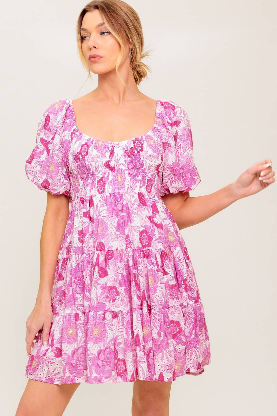 A printed woven eyelet mini dress featuring U neckline, short puff sleeve, smocked bodice and tiered skirt