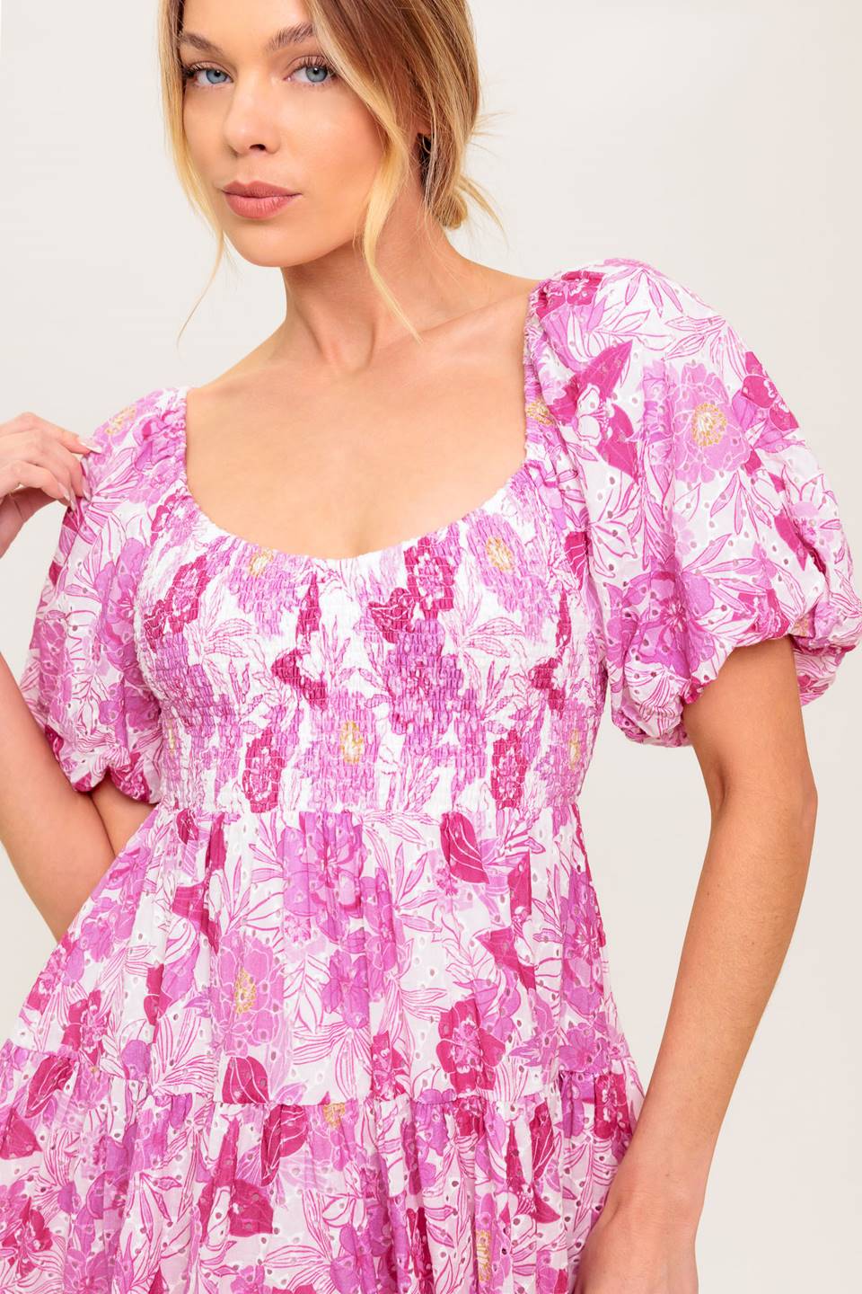 A printed woven eyelet mini dress featuring U neckline, short puff sleeve, smocked bodice and tiered skirt
