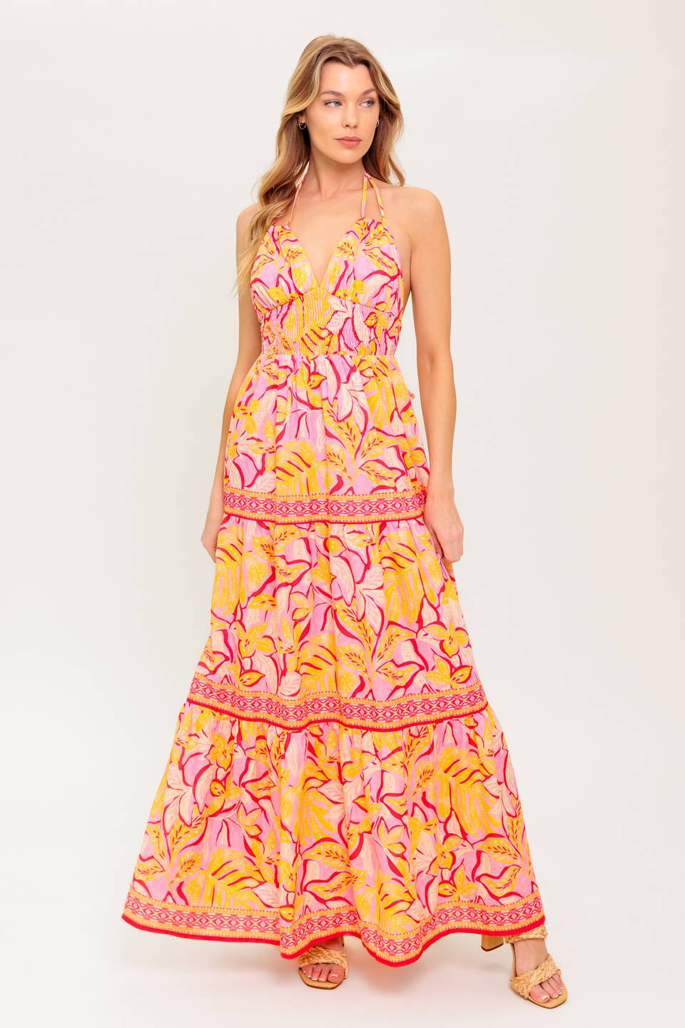 A printed woven maxi dress featuring cami top with halter tie, smocked waist yoke, tiered skirt and bare back