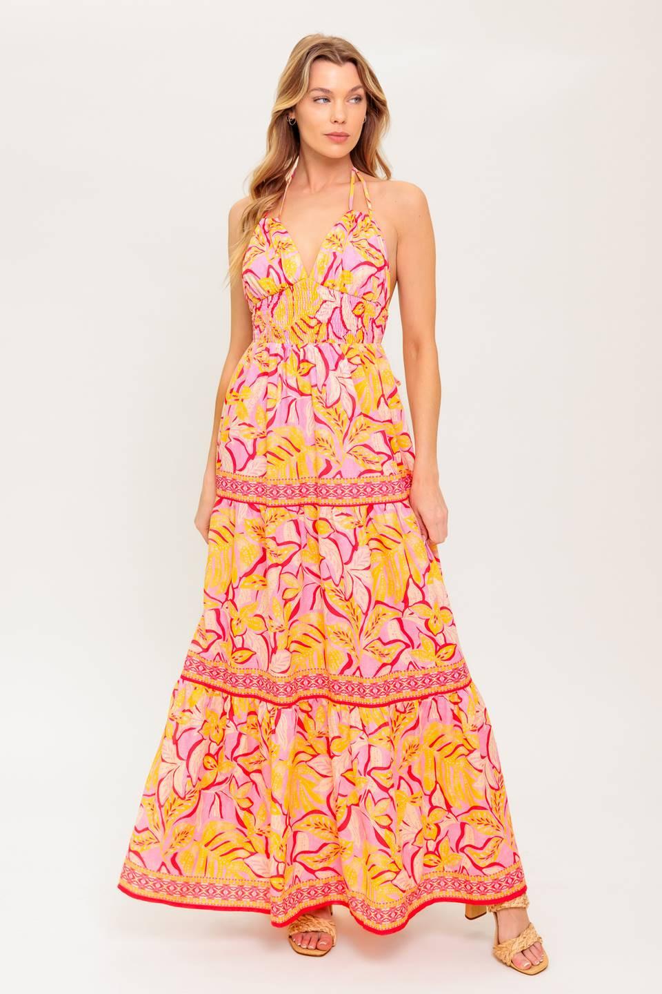 A printed woven maxi dress featuring cami top with halter tie, smocked waist yoke, tiered skirt and bare back