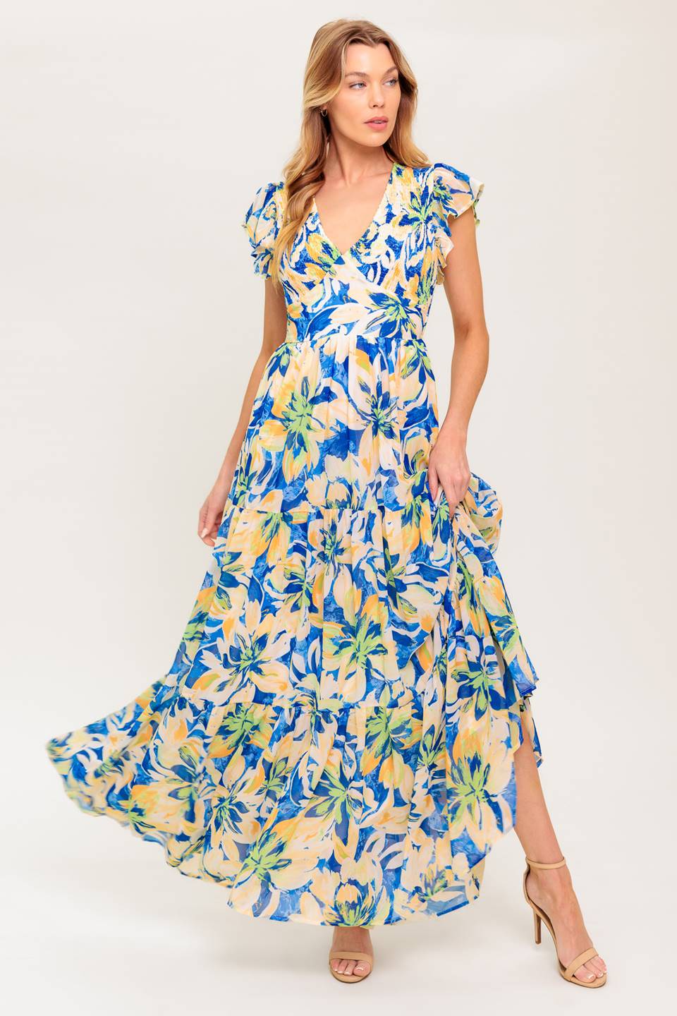 A printed woven maxi dress featuring V neckline, short flutter sleeve, smocked bodice, waist yoke and tiered skirt