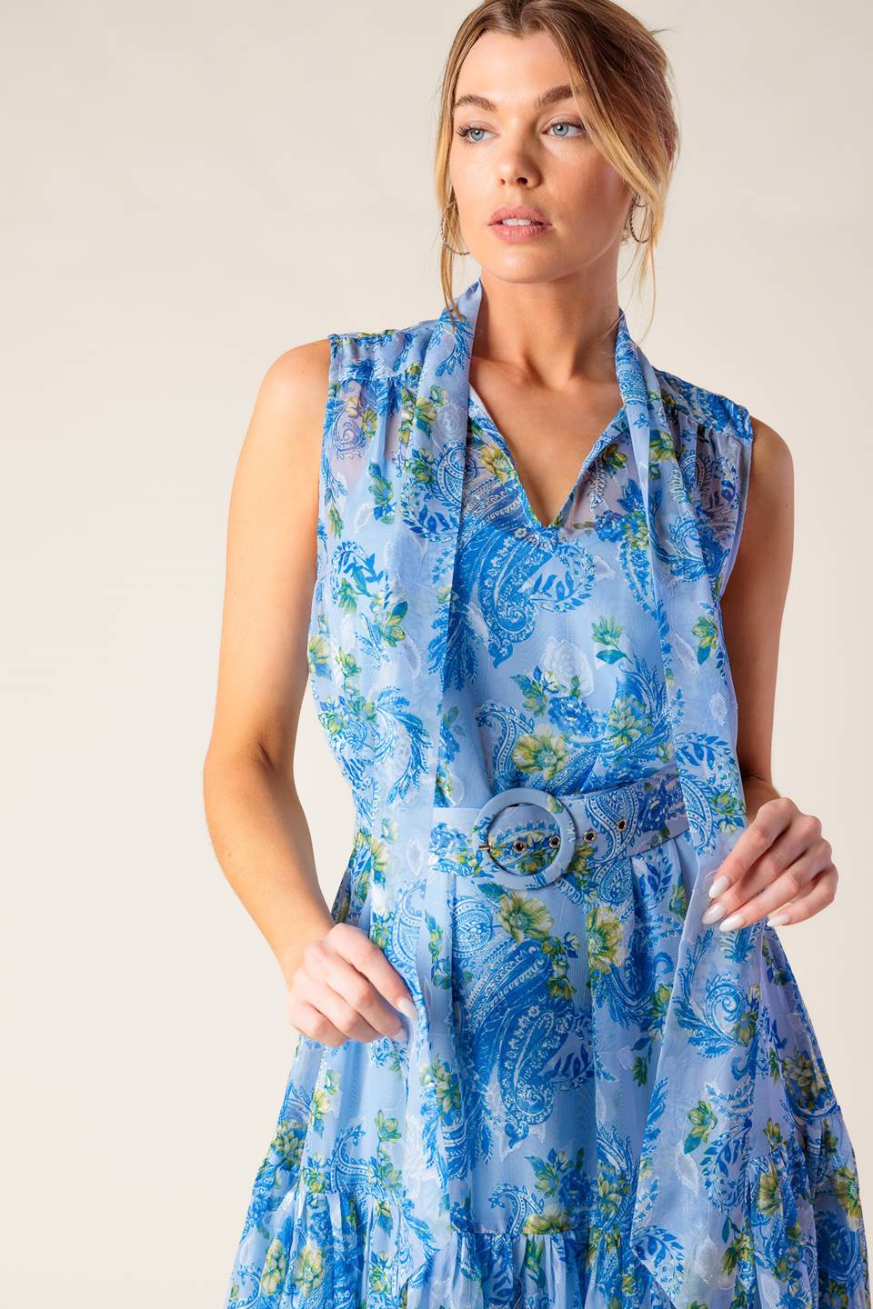 A printed woven midi dress featuring front bow tie, sleeveless, self belt and ruffled hemline