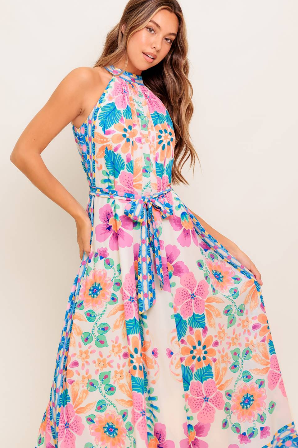 A printed woven maxi dress featuring halter neckline, self sash tie and back button closure.