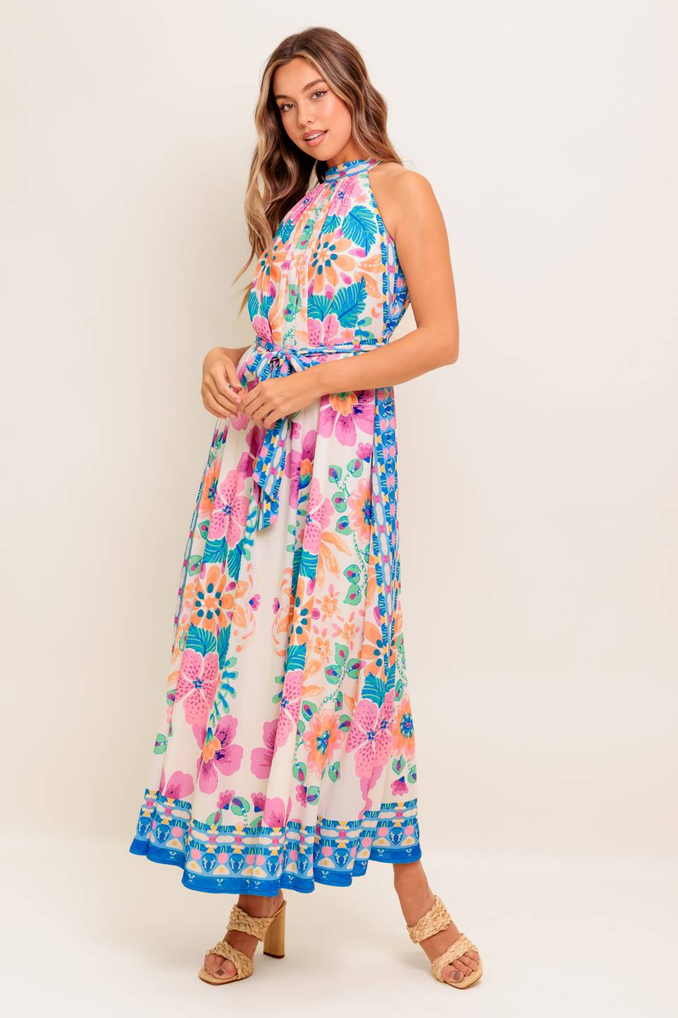 A printed woven maxi dress featuring halter neckline, self sash tie and back button closure.
