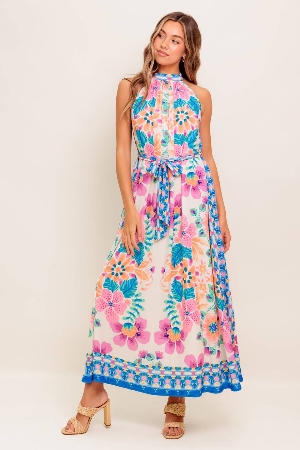 A printed woven maxi dress featuring halter neckline, self sash tie and back button closure.