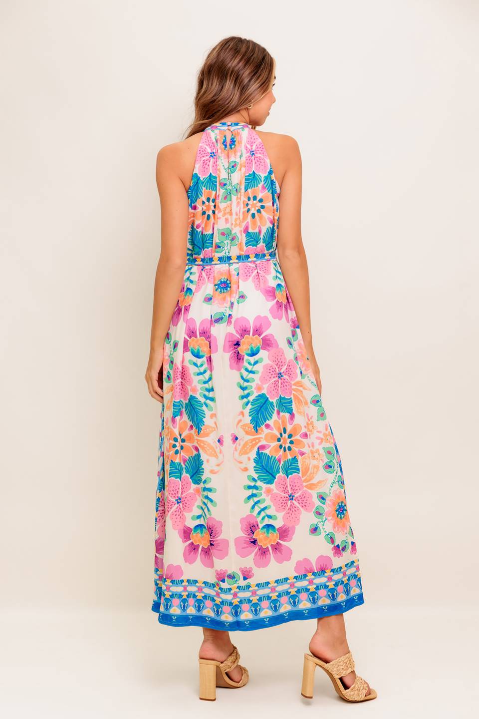 A printed woven maxi dress featuring halter neckline, self sash tie and back button closure.