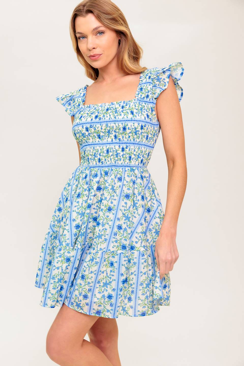 A printed woven mini dress featuring square neckline, ruffled sleeve, smocked bodice and ruffled hemline