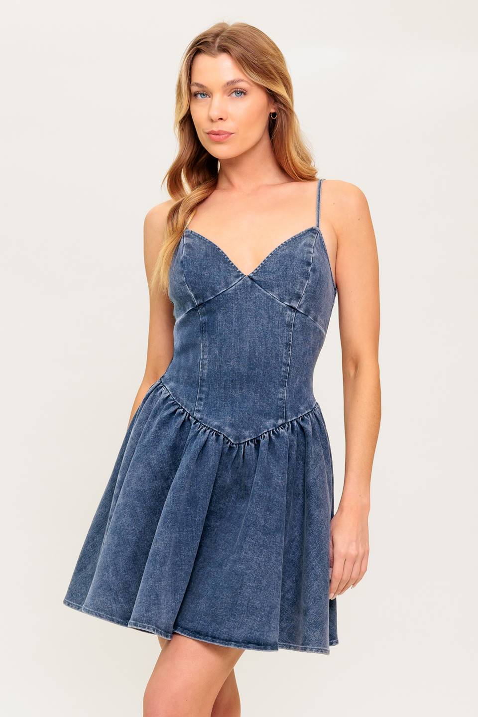 A washed denim mini dress featuring cami top, straps, basque waist line, low back and zipper closure