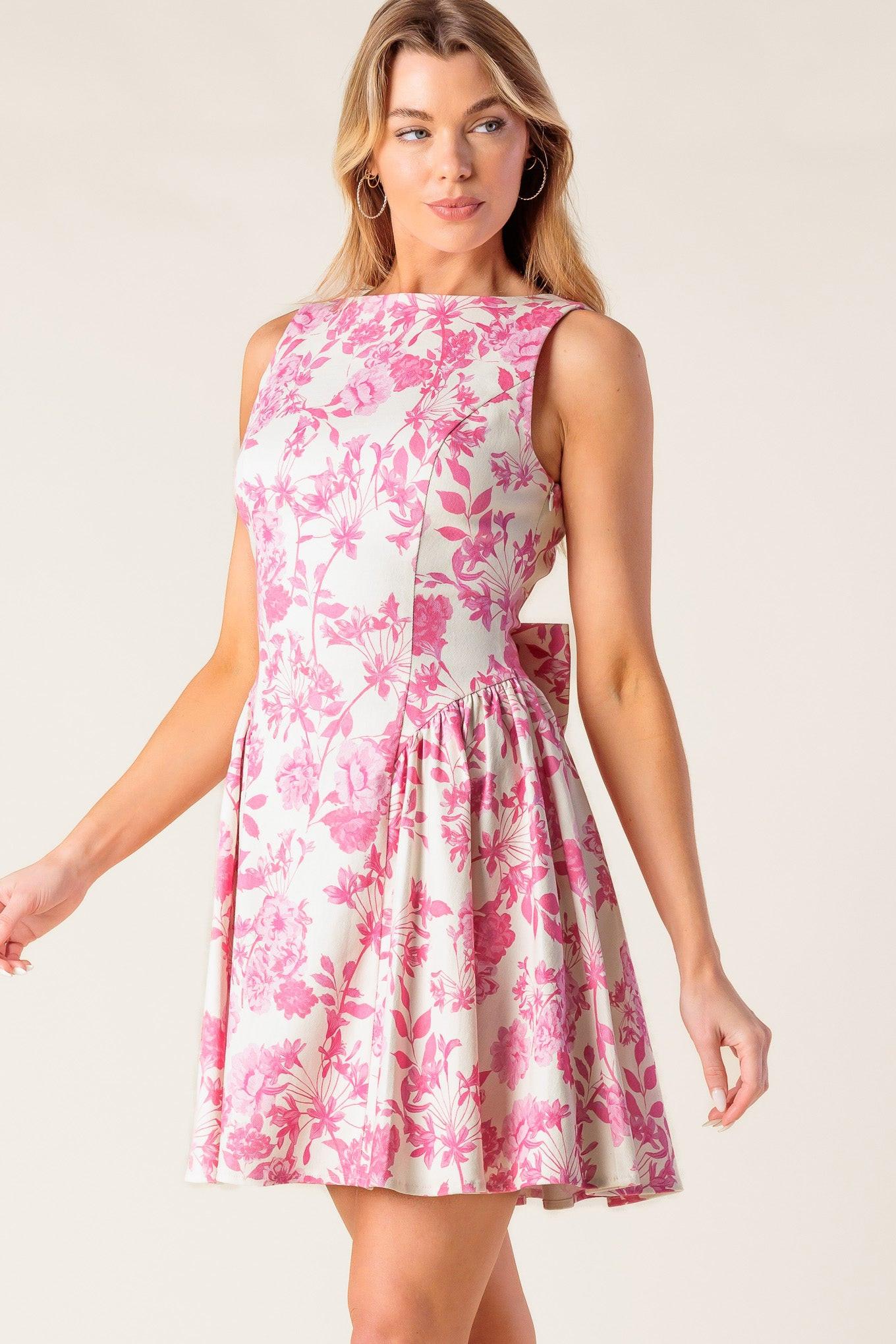 A printed woven mini dress featuring boat neckline, sleeveless, shirred side panel, bare back with bow detail and side zipper closure