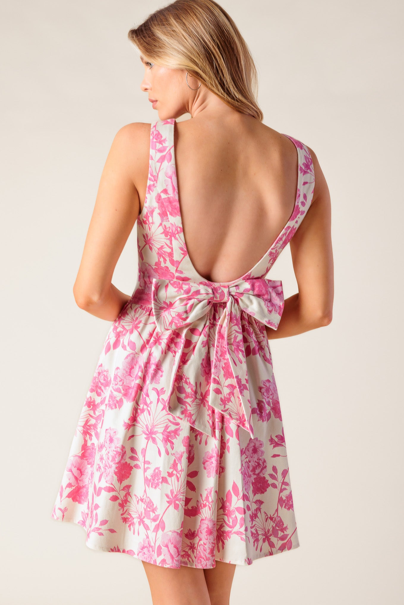 A printed woven mini dress featuring boat neckline, sleeveless, shirred side panel, bare back with bow detail and side zipper closure