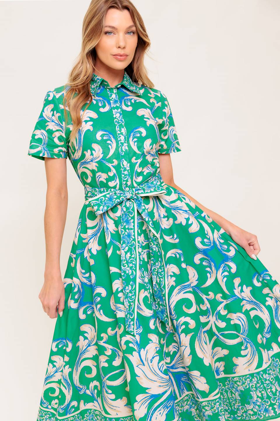 A printed woven midi dress featuring collar, short sleeve, button down, self sash tie and full skirt.