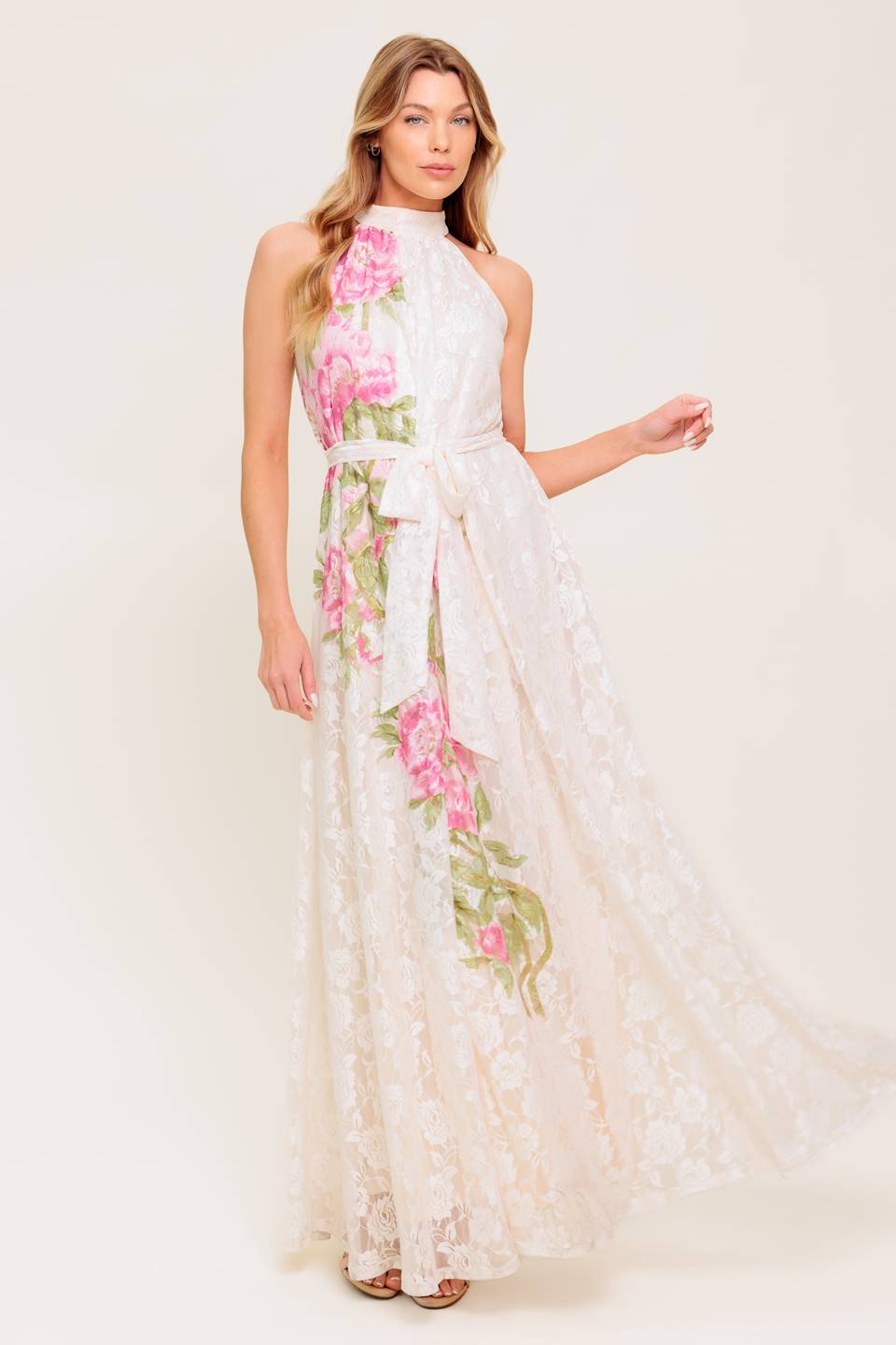 A printed woven lace maxi dress featuring halter neckline, self sash tie and back button closure.