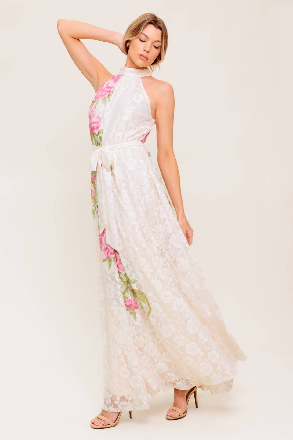 A printed woven lace maxi dress featuring halter neckline, self sash tie and back button closure.