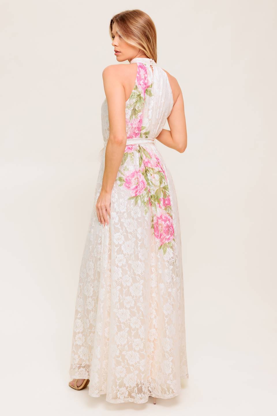 A printed woven lace maxi dress featuring halter neckline, self sash tie and back button closure.