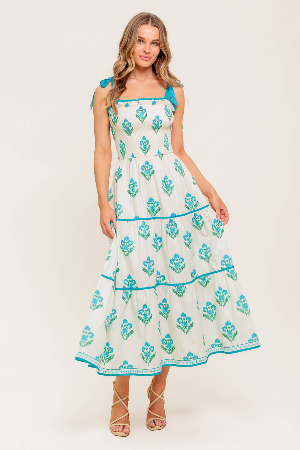 A printed woven midi dress featuring straight neckline with ruffled edge, shoulder tie, smocked bodice and tiered skirt