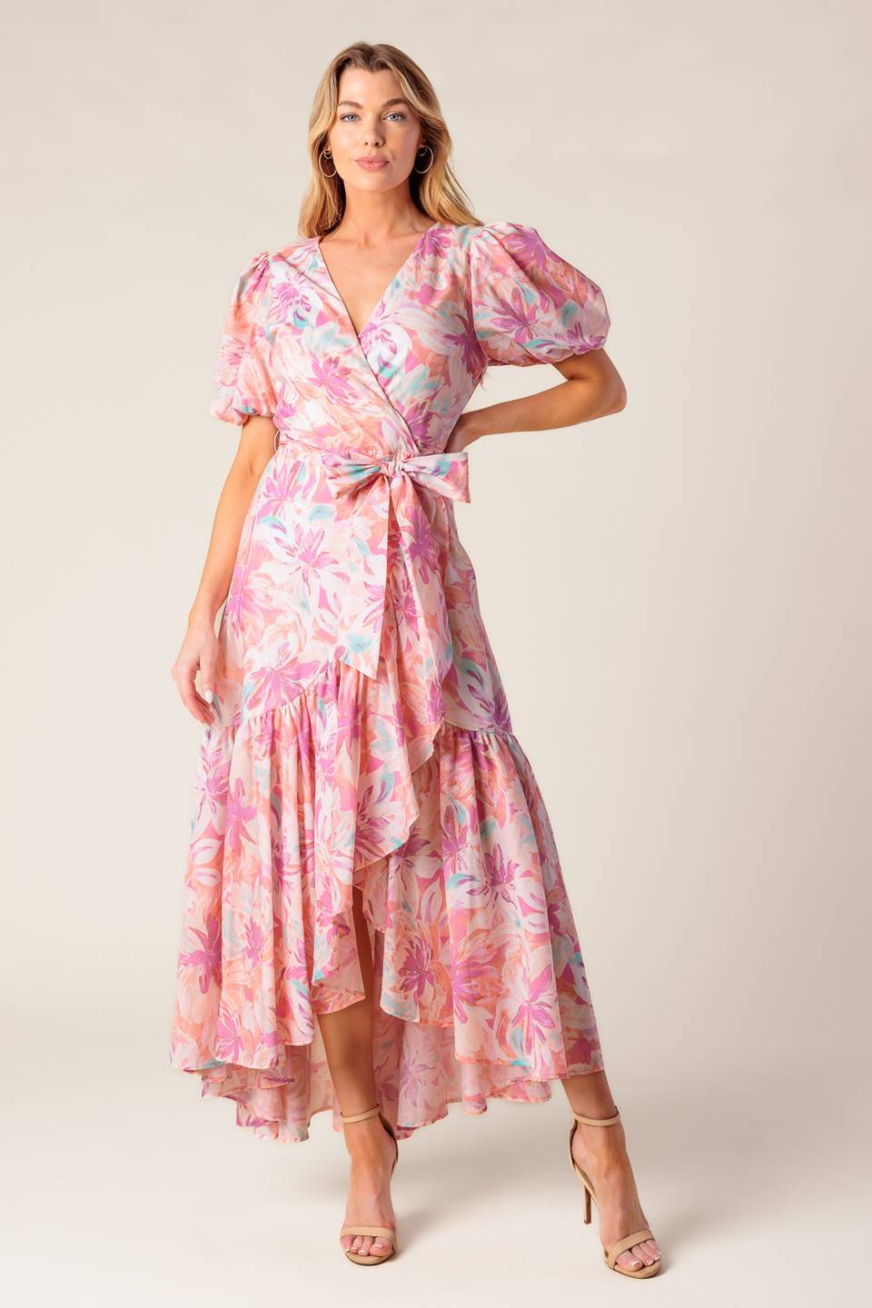 A printed woven hi-lo midi dress featuring surplice neckline, short puff sleeve, self sash tie and ruffled hemline
