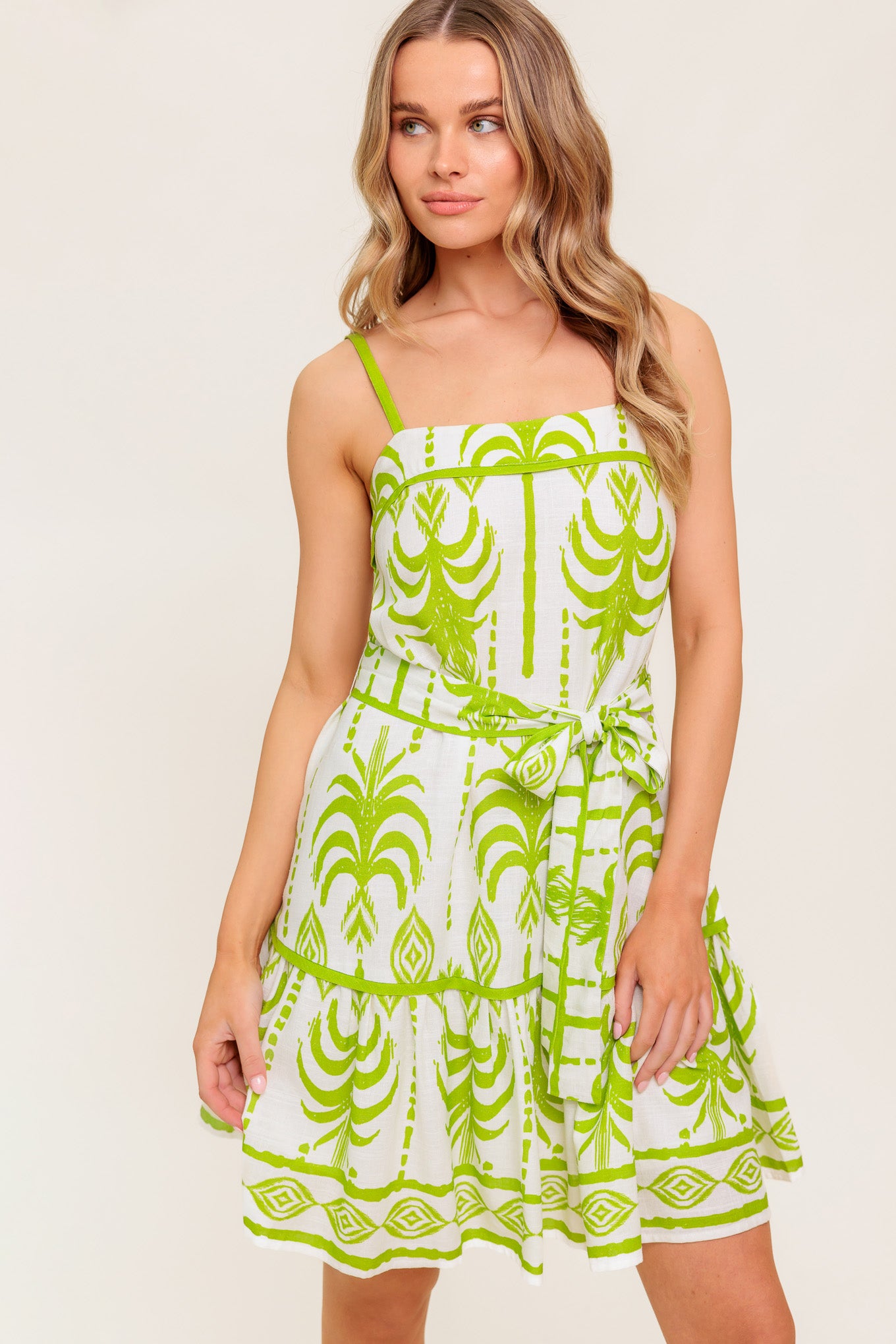 A printed woven mini dress featuring straight neckline, straps, self sash tie and ruffled hemline.