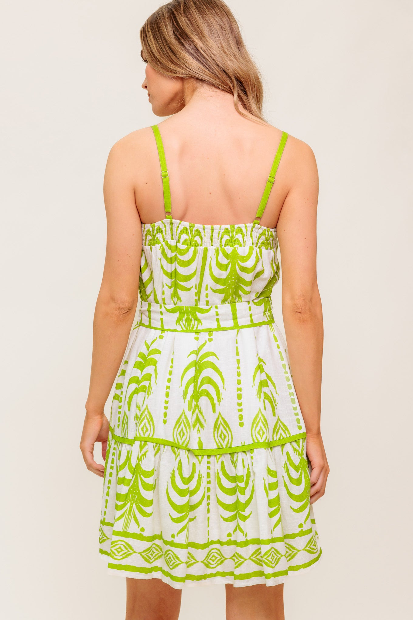A printed woven mini dress featuring straight neckline, straps, self sash tie and ruffled hemline.