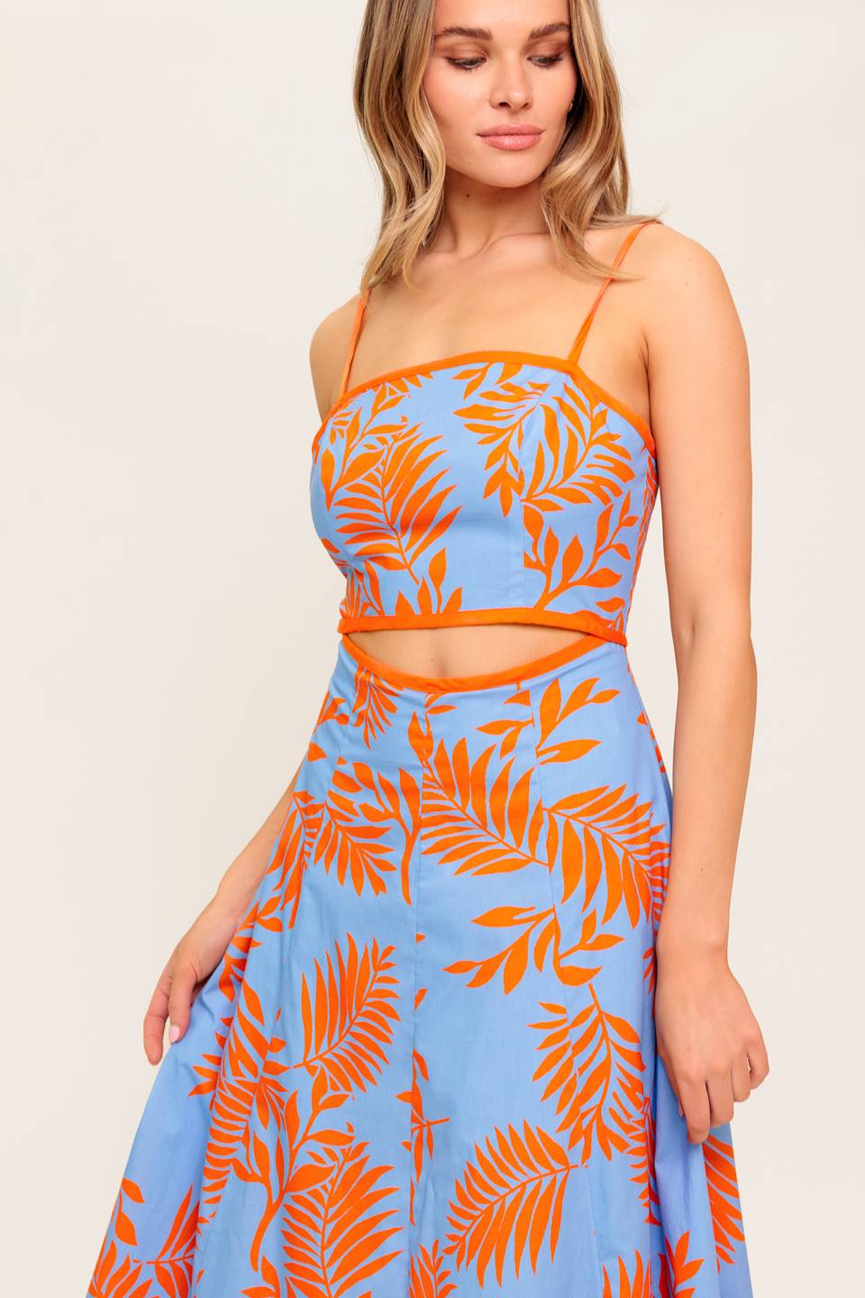 A printed woven midi dress featuring straight neckline, straps, front waist cut out, circle skirt and back zipper closure.