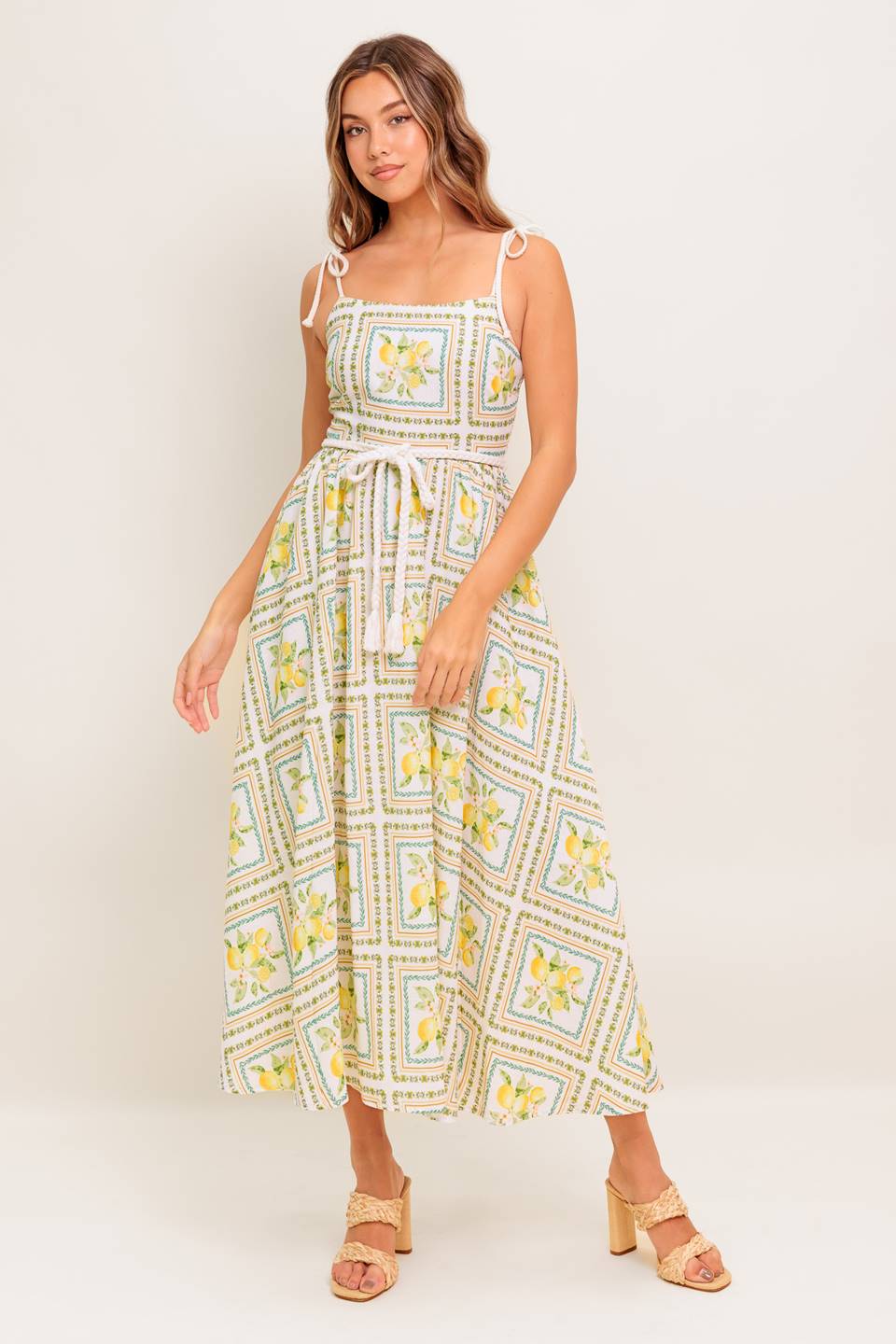 A printed woven midi dress featuring straight neckline, braided straps and belt, circle skirt and smocked back bodice