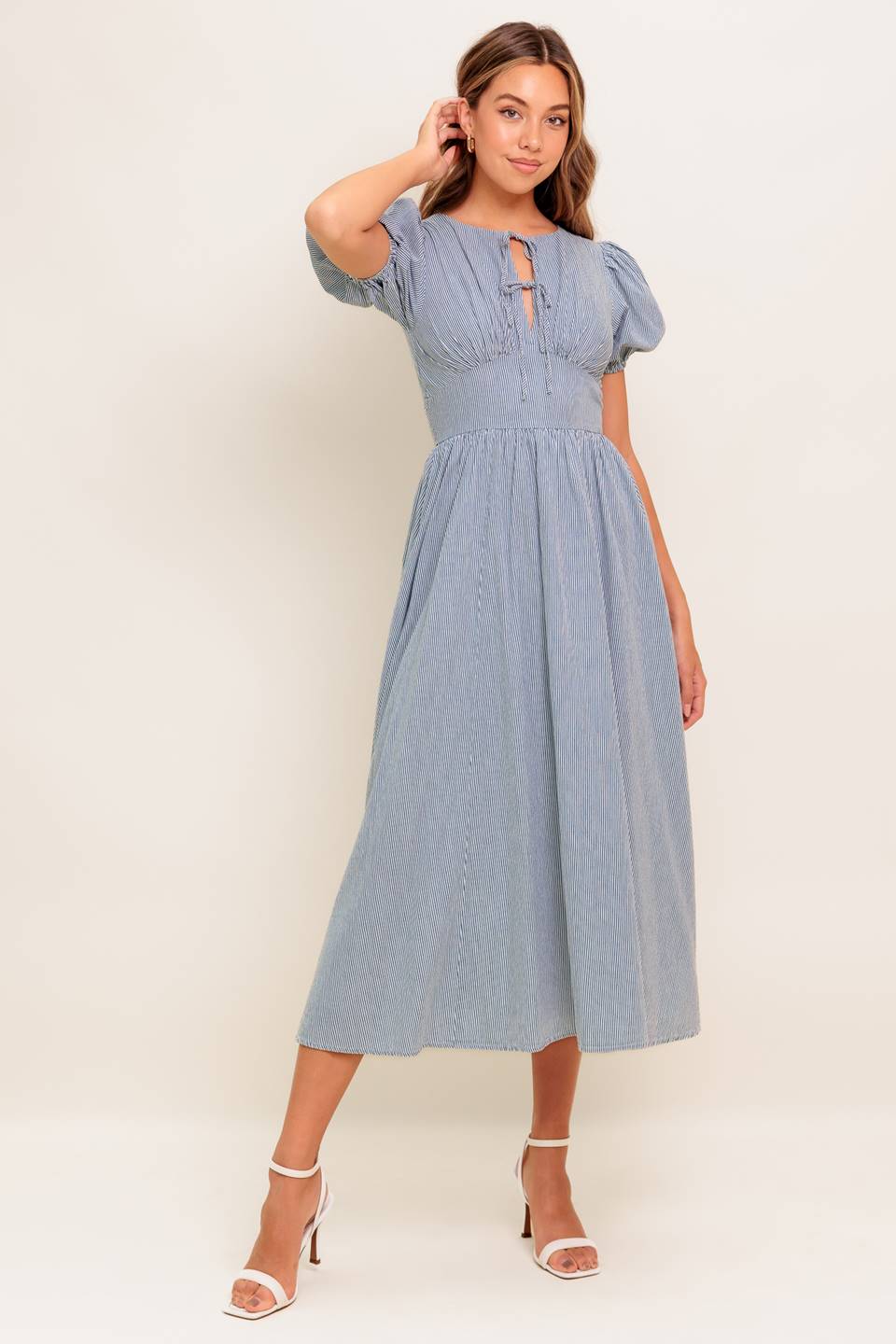 A striped woven midi dress featuring round neckline, front bow ties, short puff sleeve, waist yoke, full skirt and back zipper closure.