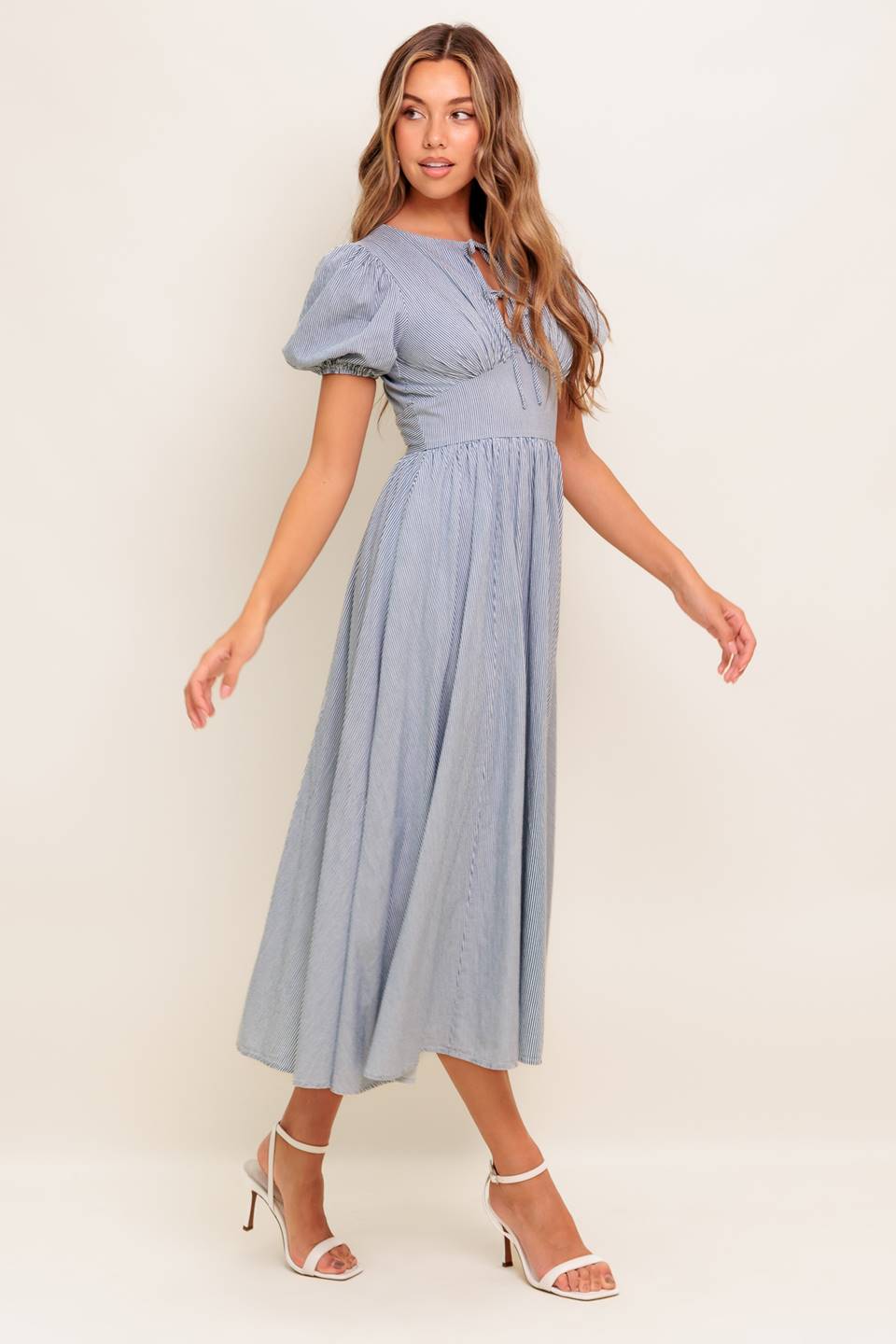 A striped woven midi dress featuring round neckline, front bow ties, short puff sleeve, waist yoke, full skirt and back zipper closure.