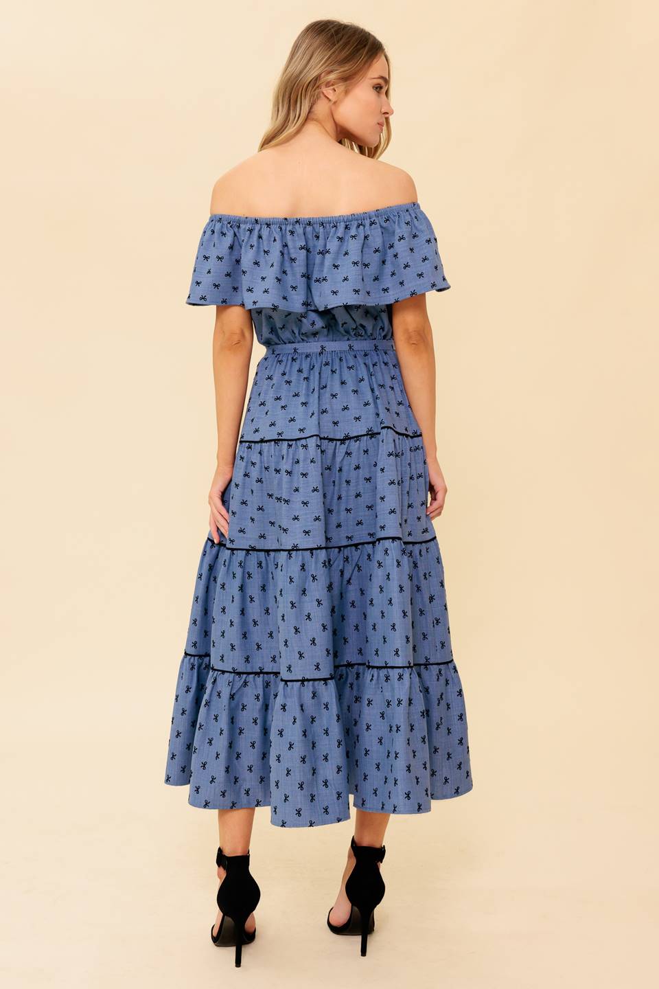 A textured woven midi dress featuring off shoulder neckline, flounce, elasticized waist, self sash tie and tiered skirt