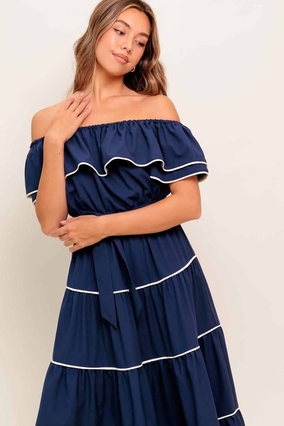 A solid navy woven midi dress featuring off shoulder neckline with flounce, elasticized waist, self sash tie and tiered skirt