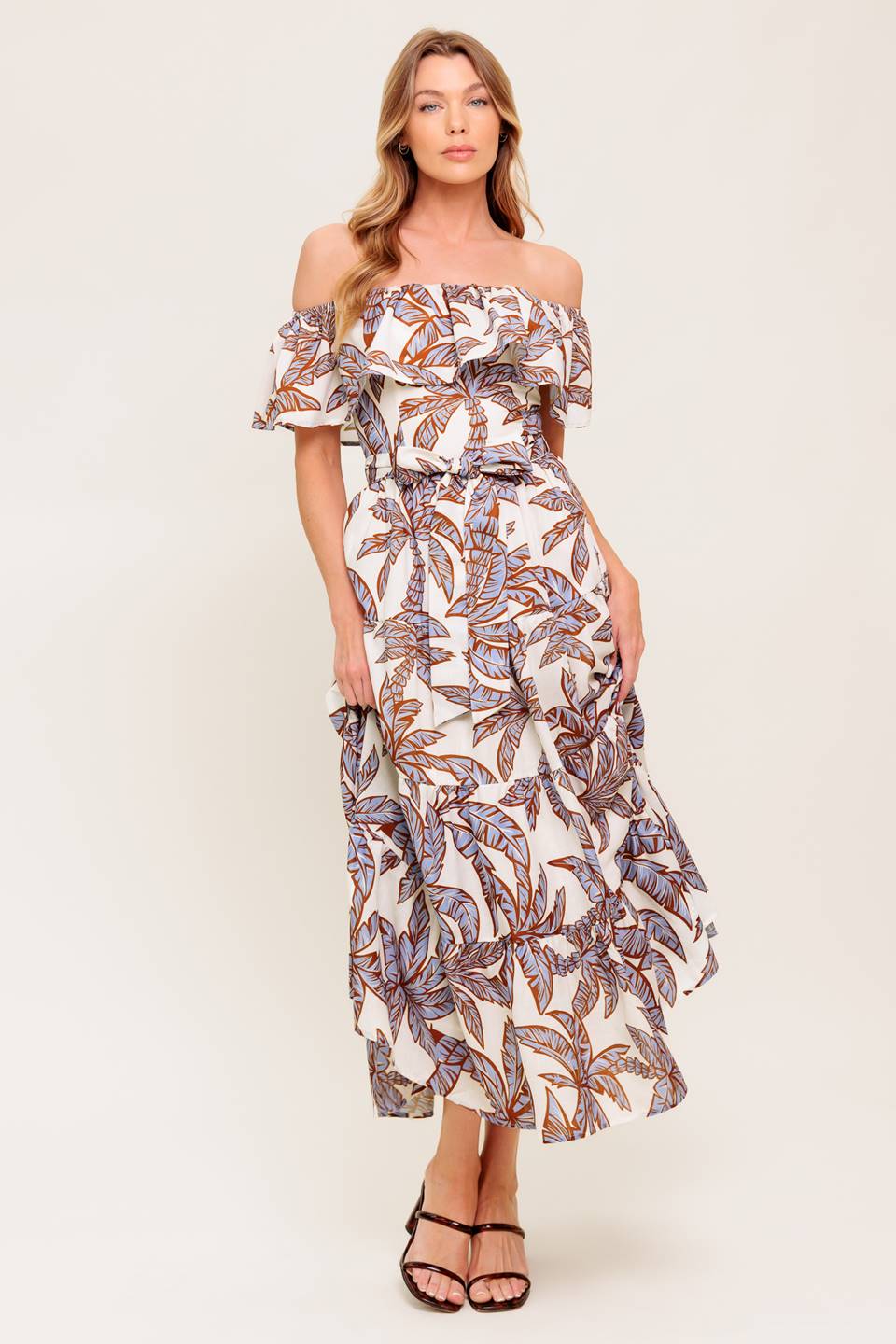 A printed woven midi dress featuring off shoulder neckline, flounce, elasticized waist with self sash tie and tiered skirt.
