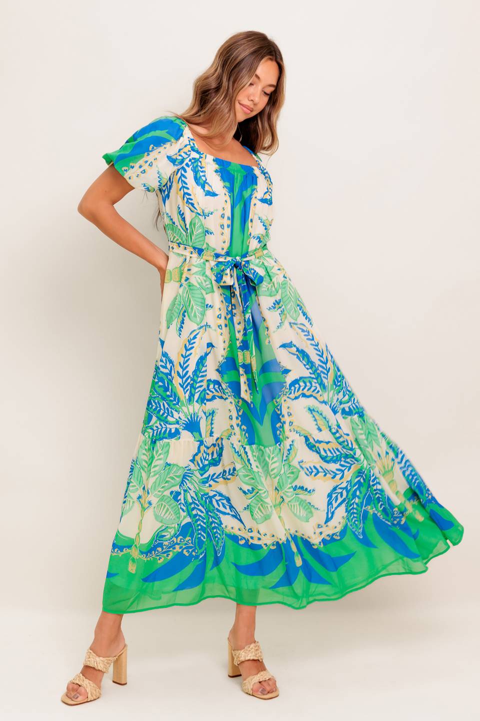 A printed woven maxi dress featuring square neckline, short puff sleeve, self sash tie and ruffled hemline