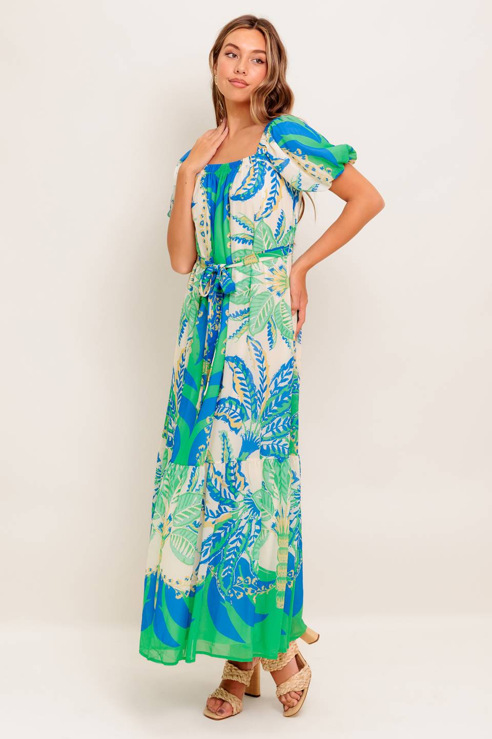 A printed woven maxi dress featuring square neckline, short puff sleeve, self sash tie and ruffled hemline