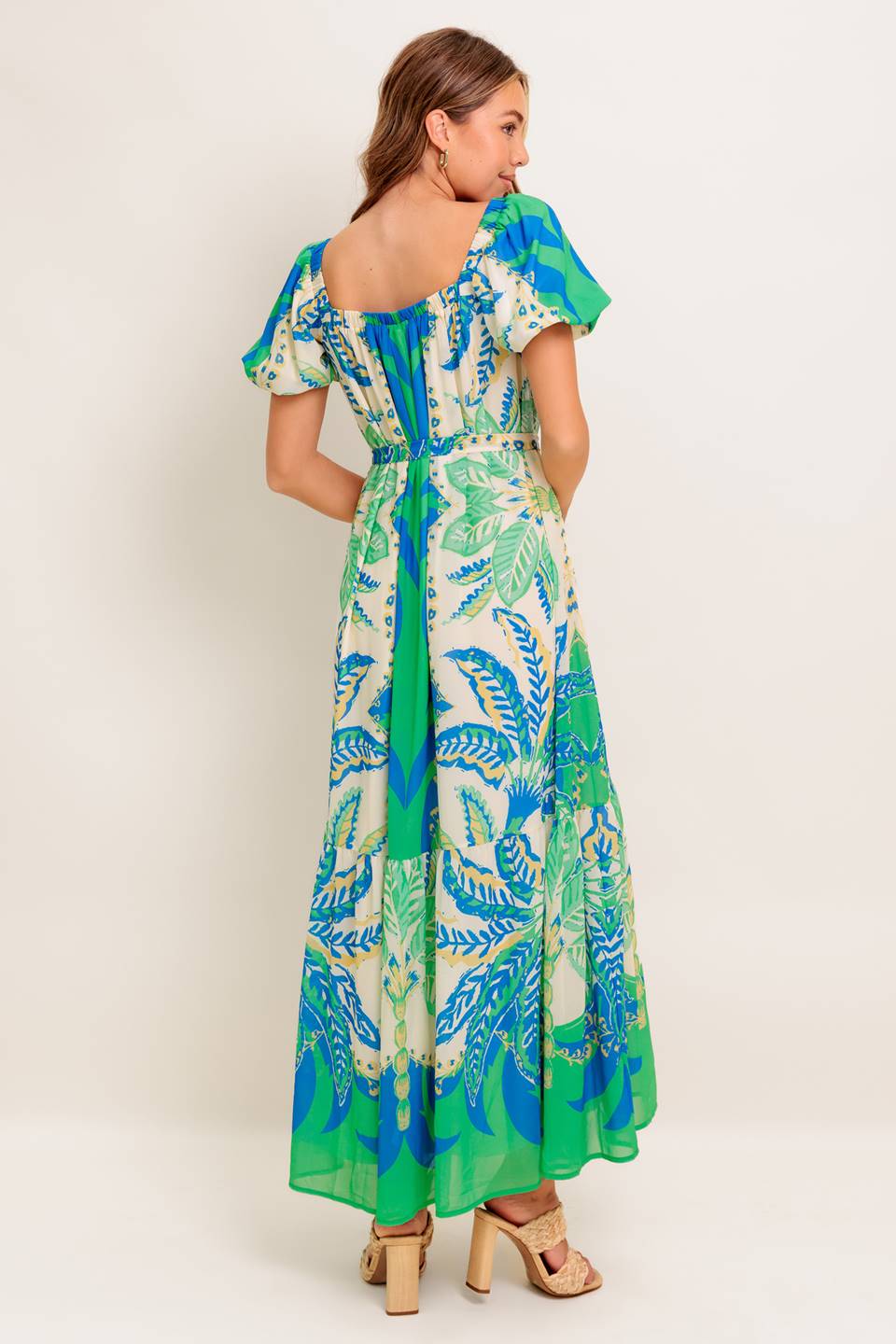 A printed woven maxi dress featuring square neckline, short puff sleeve, self sash tie and ruffled hemline