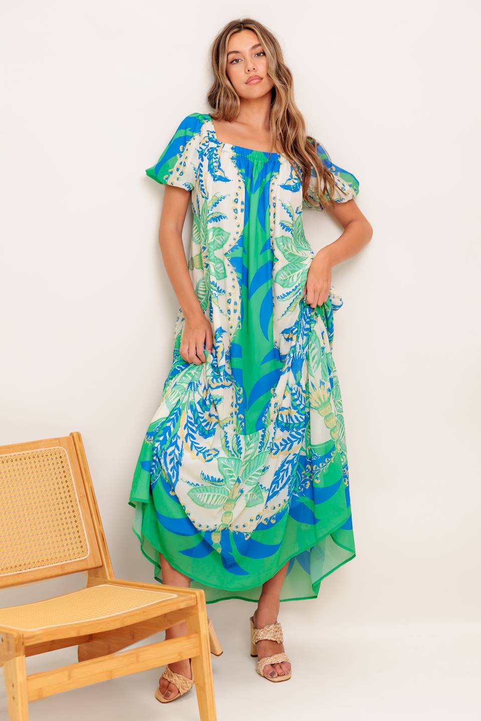 A printed woven maxi dress featuring square neckline, short puff sleeve, self sash tie and ruffled hemline