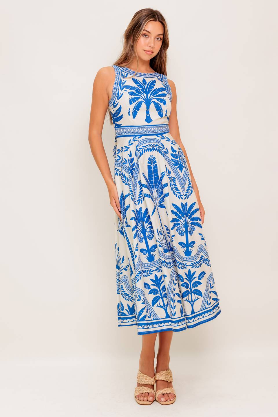 A printed woven midi dress featuring round neckline, sleeveless, circle skirt and tie back with zipper closure